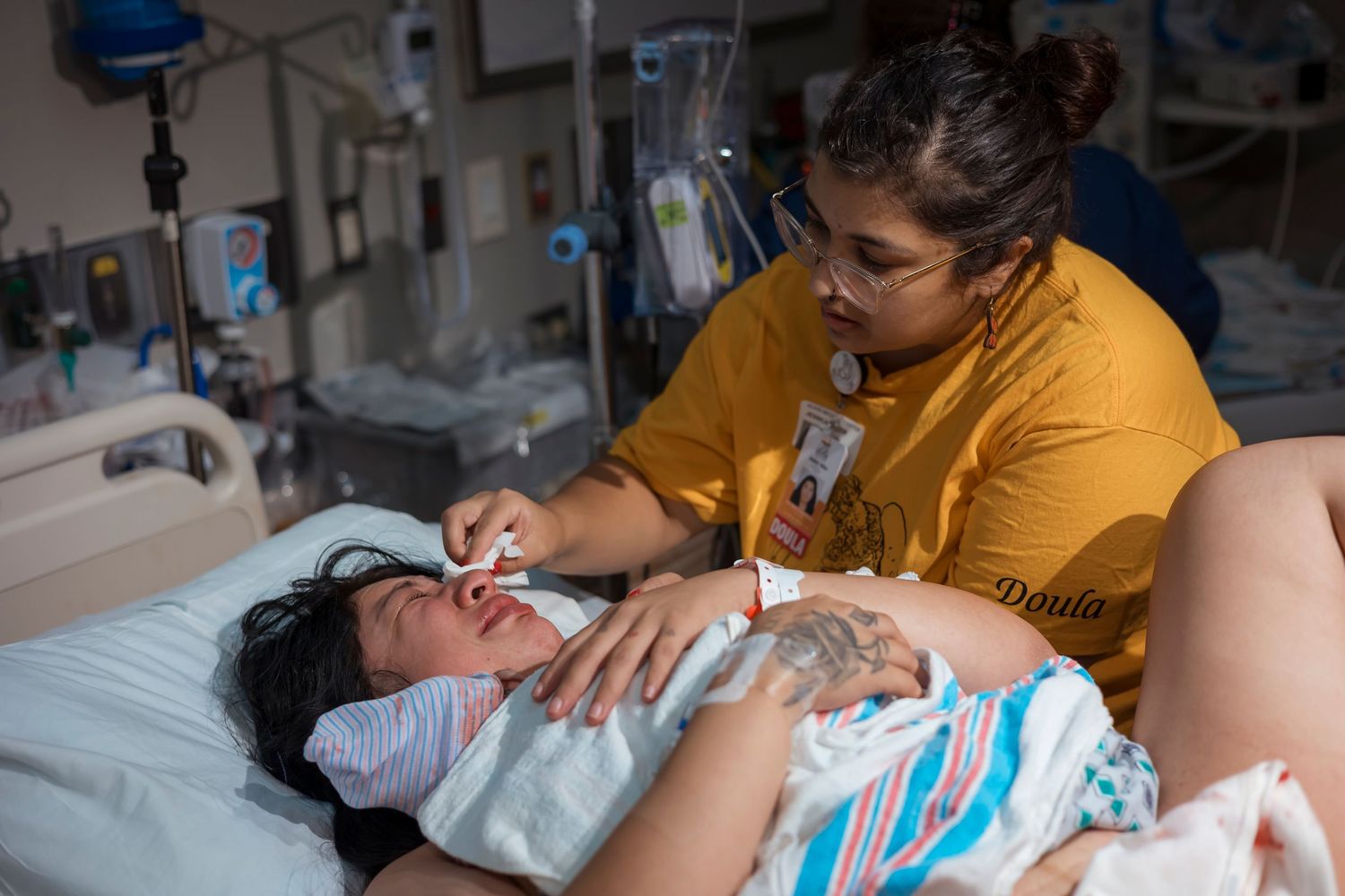 Delivery room scene with medical staff in yellow providing care.