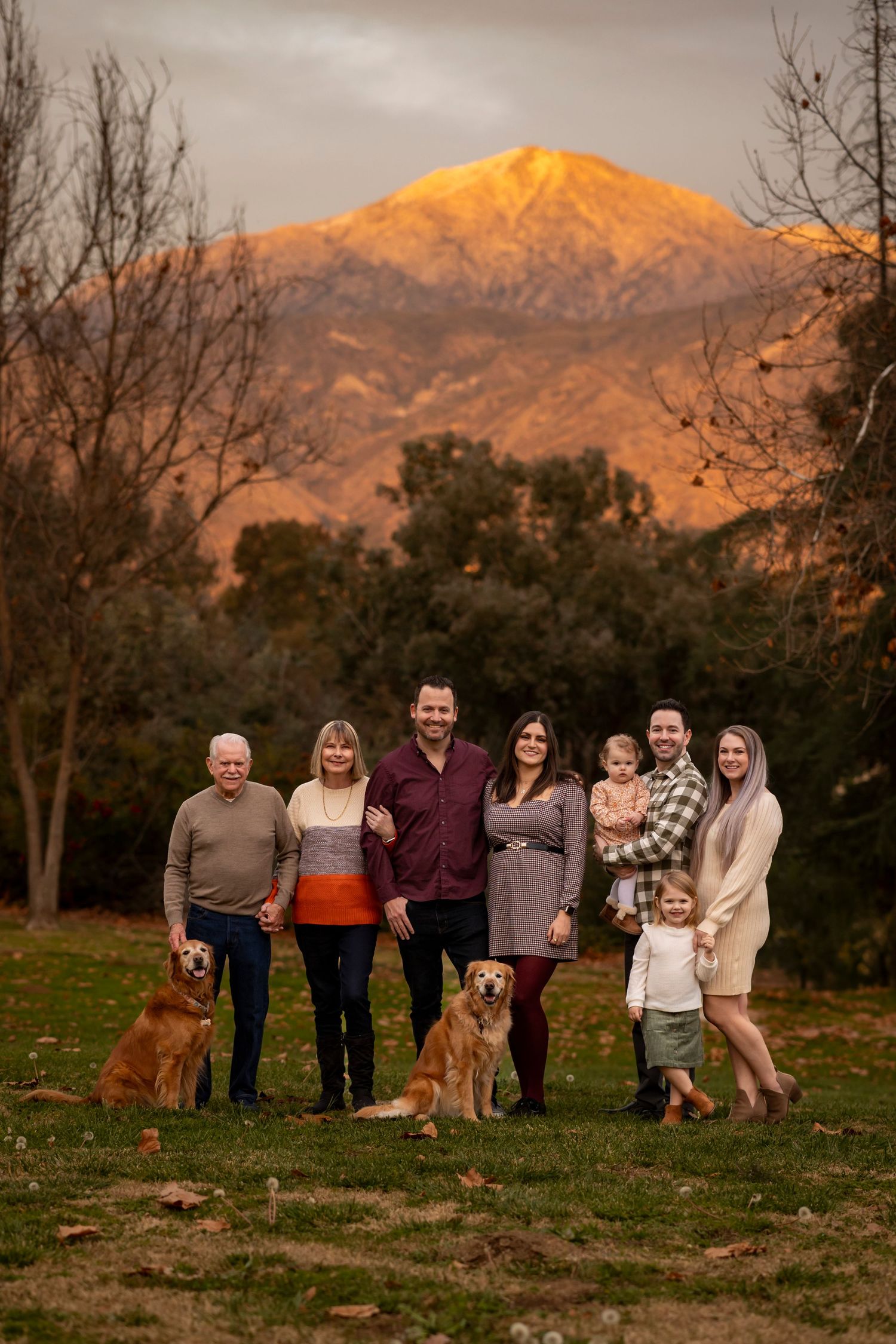 A group of people and dogs gather at sunset with snow-capped mountains creating a beautiful backdrop in the distance in Yucaipa.