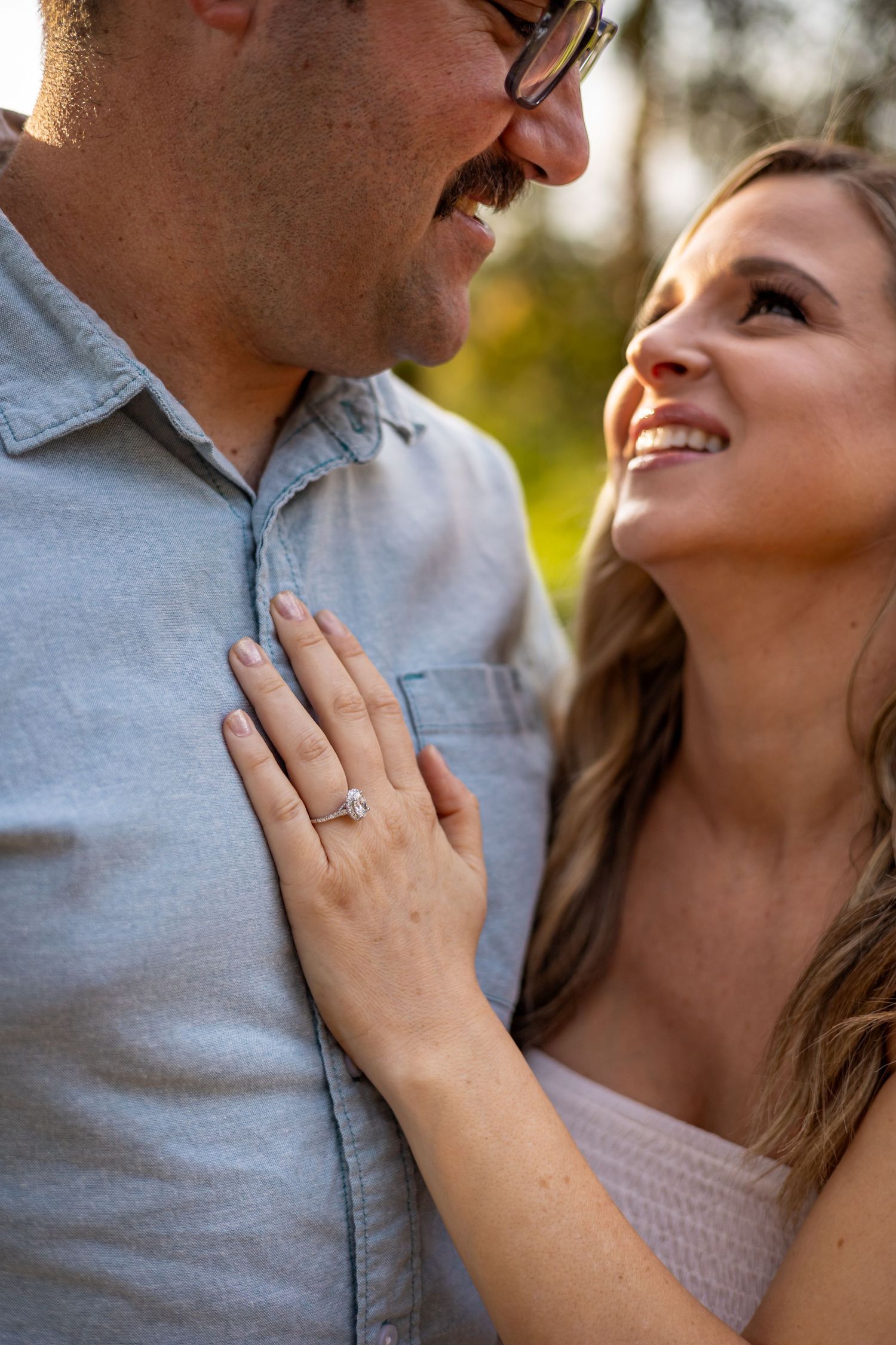 Happy engaged couple sharing a close moment while showing off new ring.