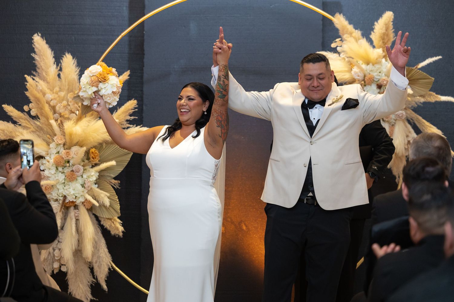 Lively dance celebration at a wedding reception with decorative gold accents and dramatic lighting.