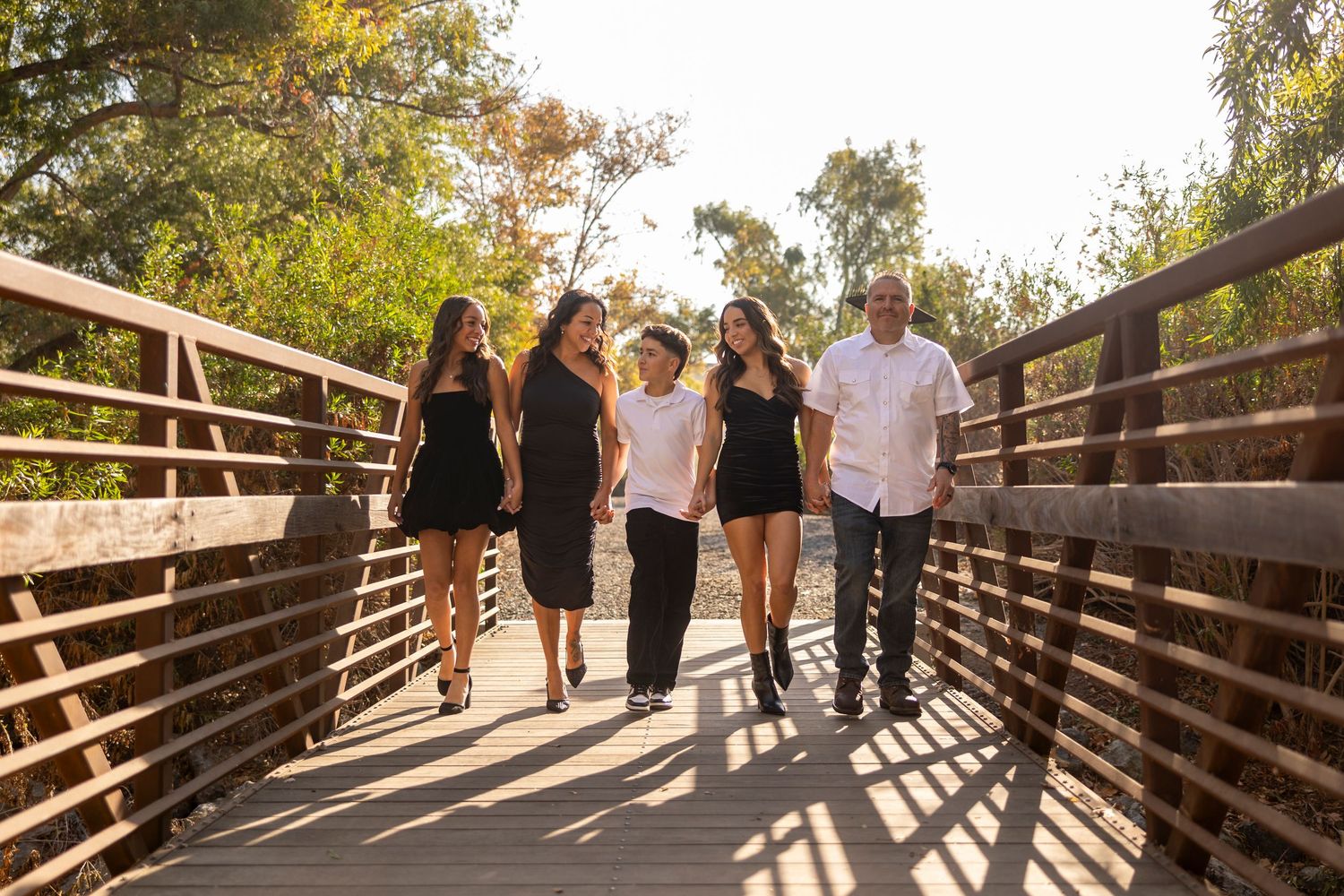 A group walks together on a wooden bridge during an outdoor photo session.