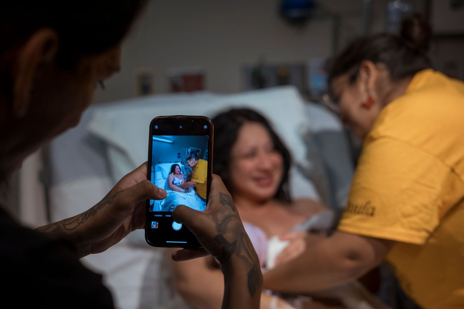 Someone takes photo with phone during hospital delivery scene.