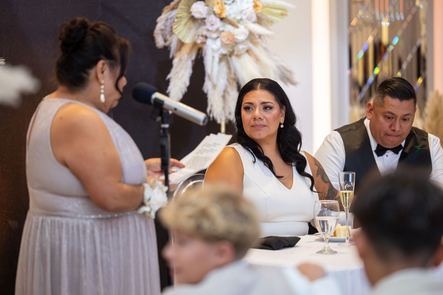 Wedding reception speech being given during dinner service with elegant decor.