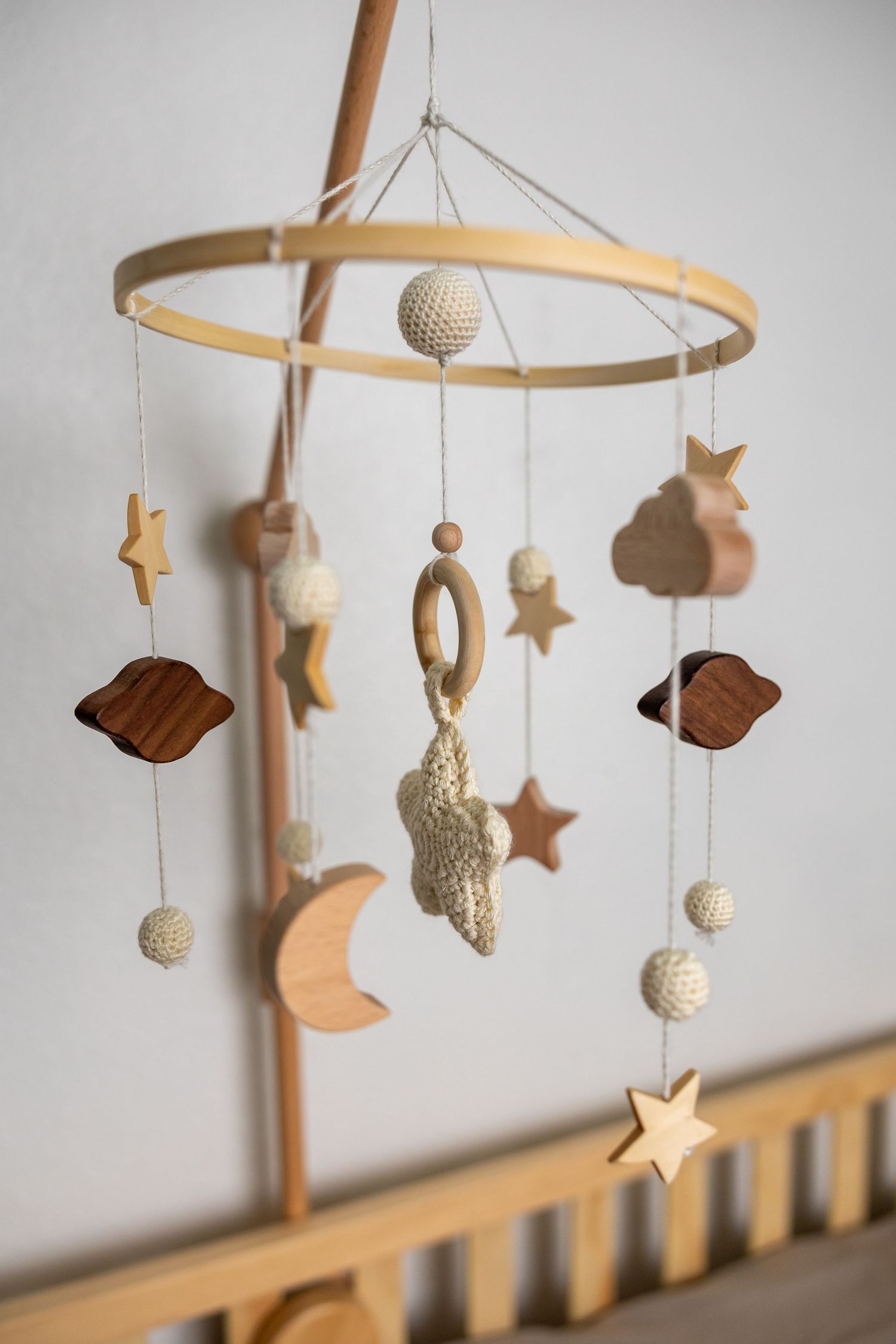 Wooden nursery mobile with stars and moons hanging from circular frame.