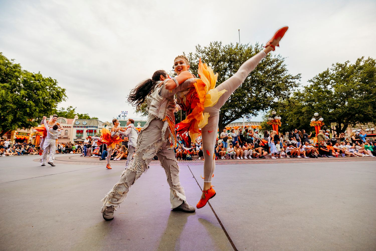 Street performers doing acrobatic moves during an outdoor show with crowd in background.