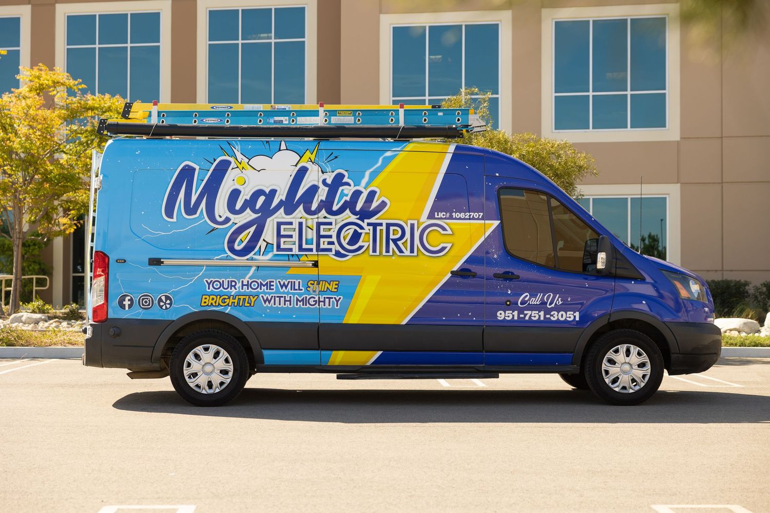 Blue and yellow branded service vans parked in line outside a commercial building with glass windows.