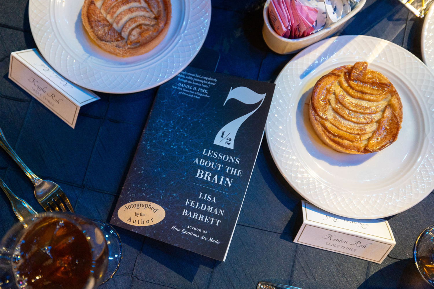 Aerial view of various coffee cups, plates of pancakes, and restaurant menus arranged on a dark blue surface.