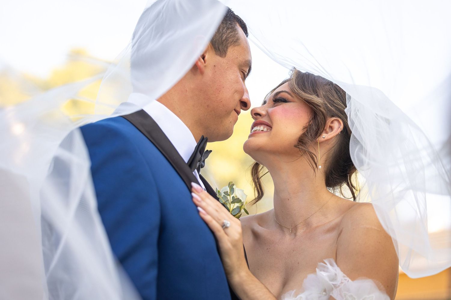 Romantic moment captured under bridal veil with soft natural lighting.