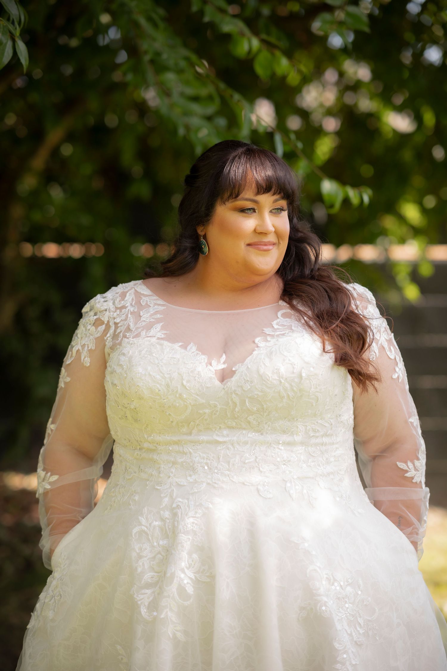 Close-up details of a white lace wedding dress with sheer sleeves in natural lighting.
