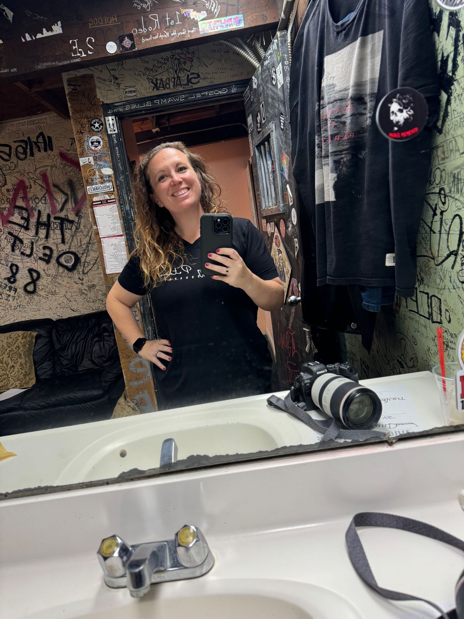 Mirror selfie taken in what appears to be a bathroom with graffiti covered walls.
