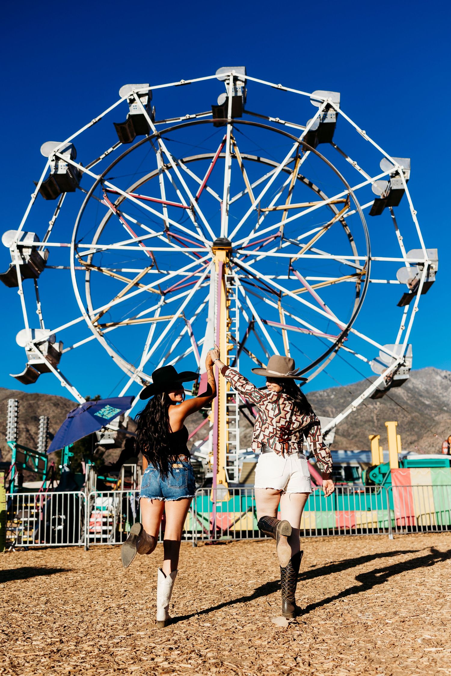 White ferris wheel stands against bright blue sky at desert festival grounds.