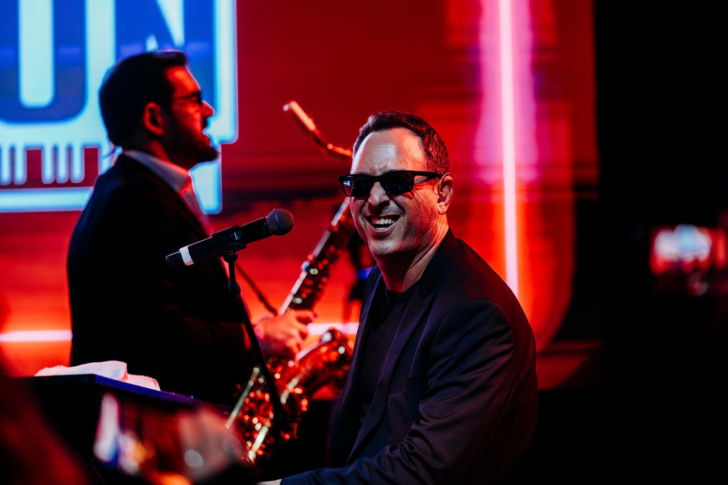 Two musicians perform together under vibrant red and blue stage lighting at indoor venue in Garden Grove.