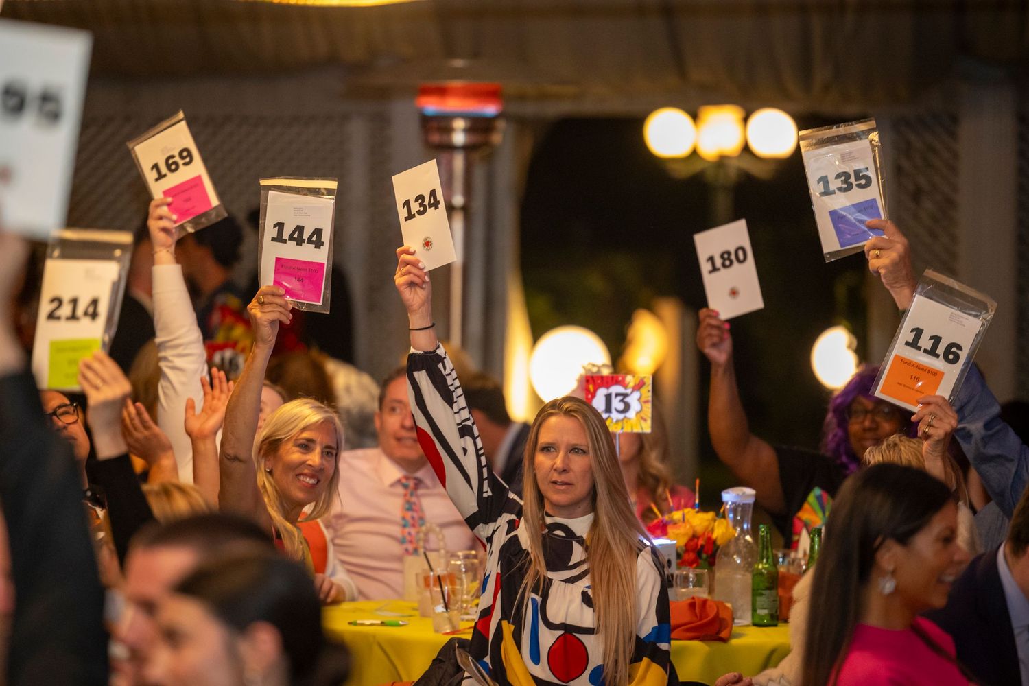 Attendees holding up numbered bidding cards during a charity auction event.