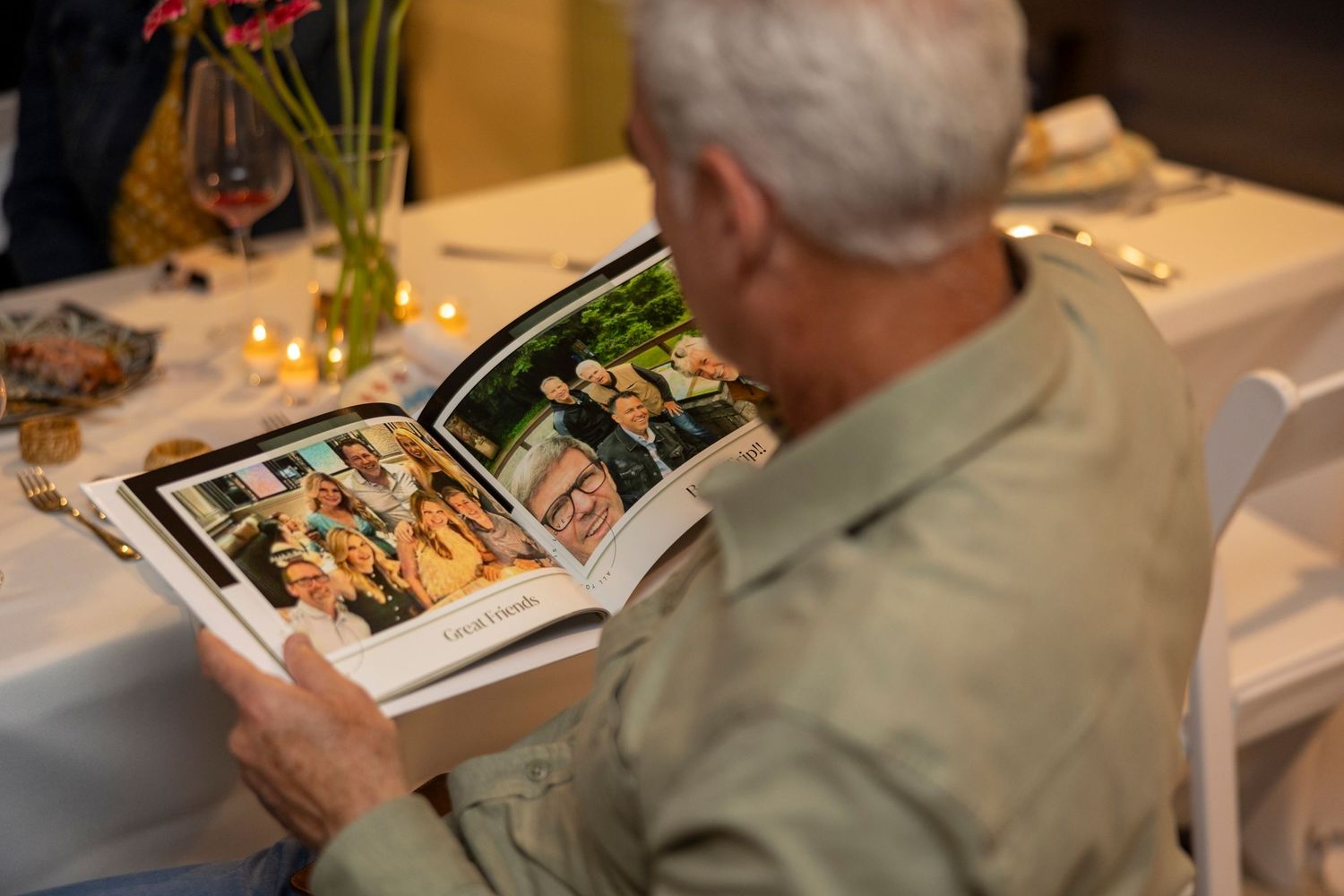 Person reviewing food photos in a cookbook or menu at a dining table.