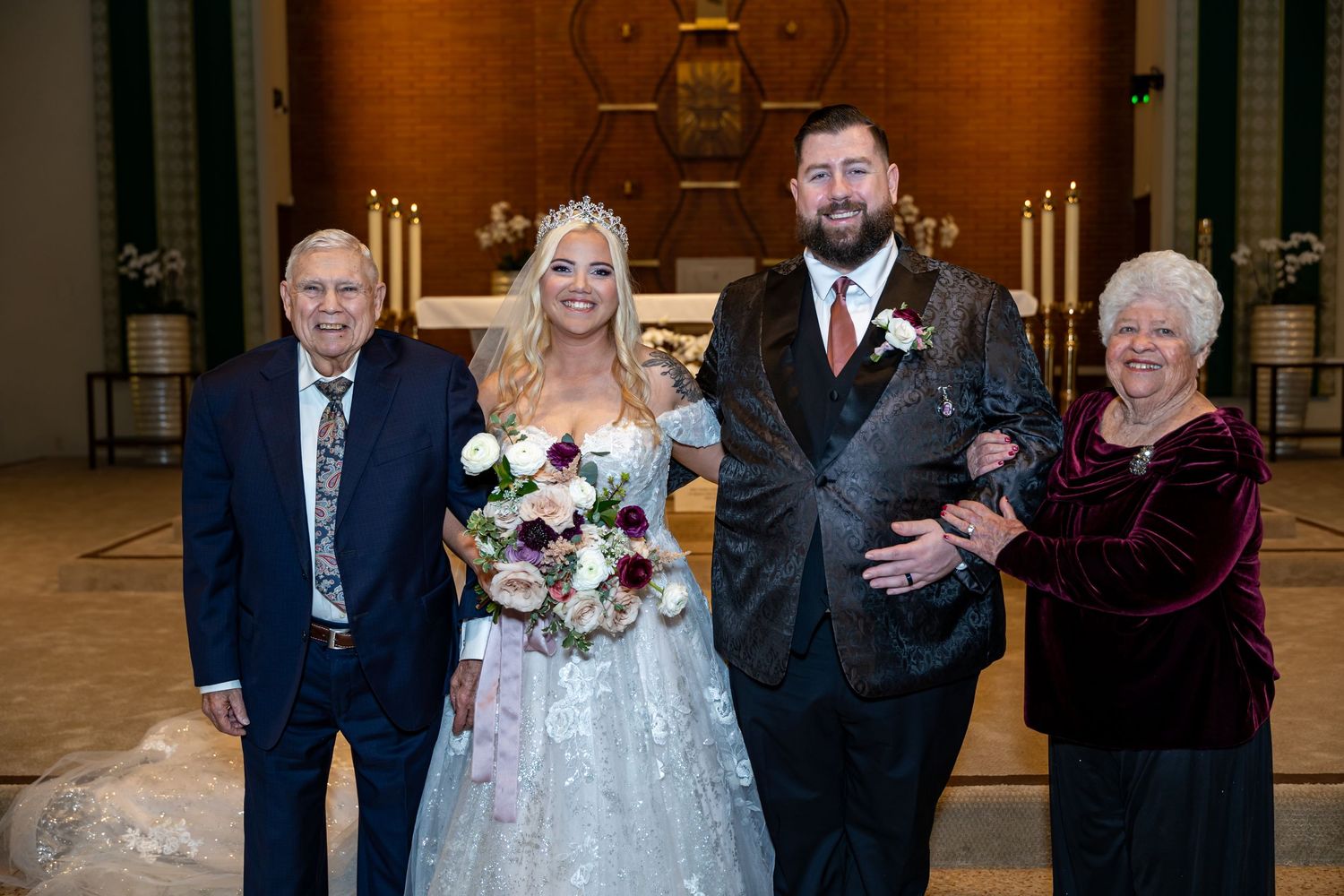 Wedding party members pose together in a church sanctuary with candles and altar in the background in Orange.