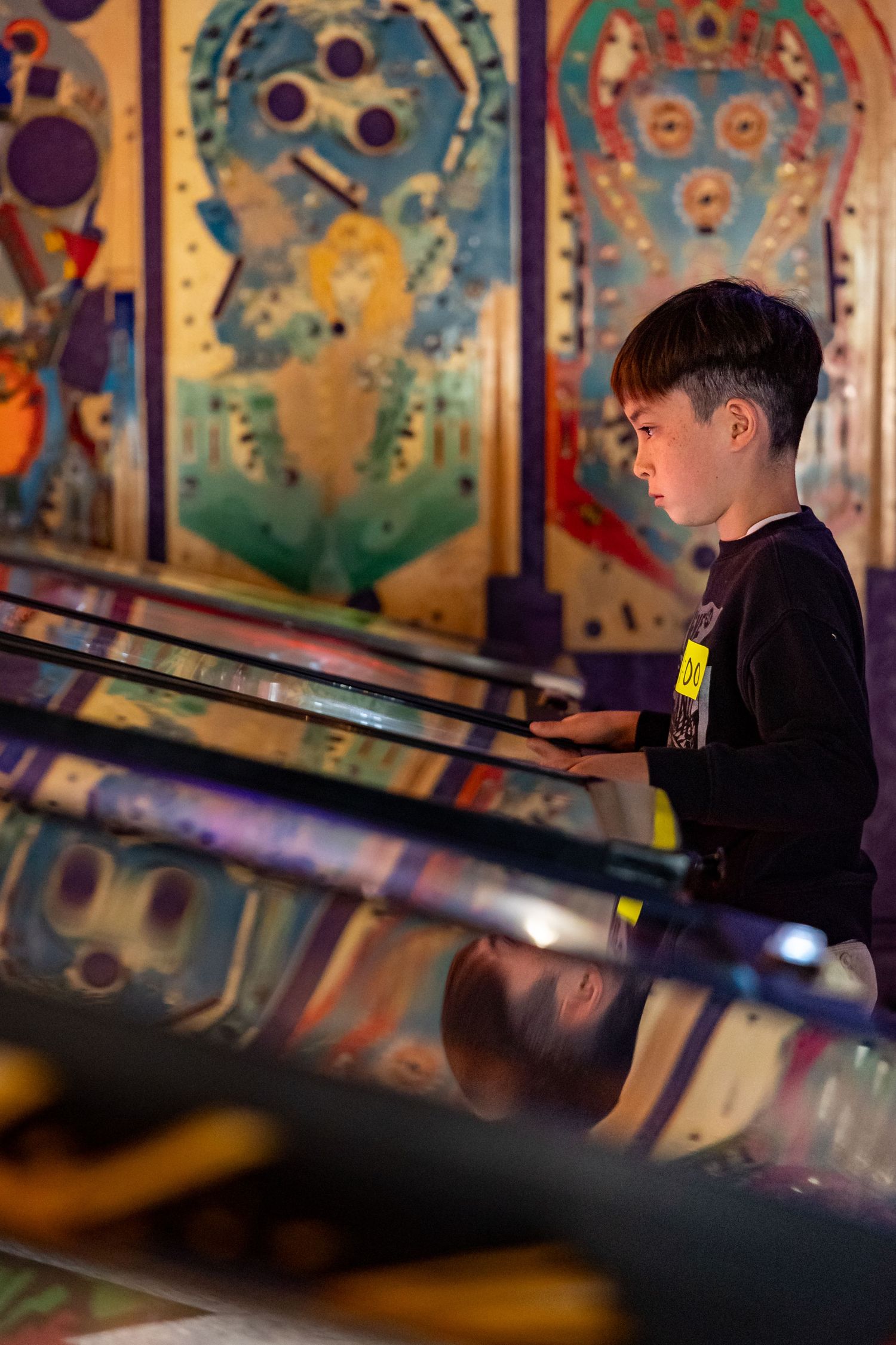Vintage pinball machines line up against a wall with colorful artwork and lighting effects.