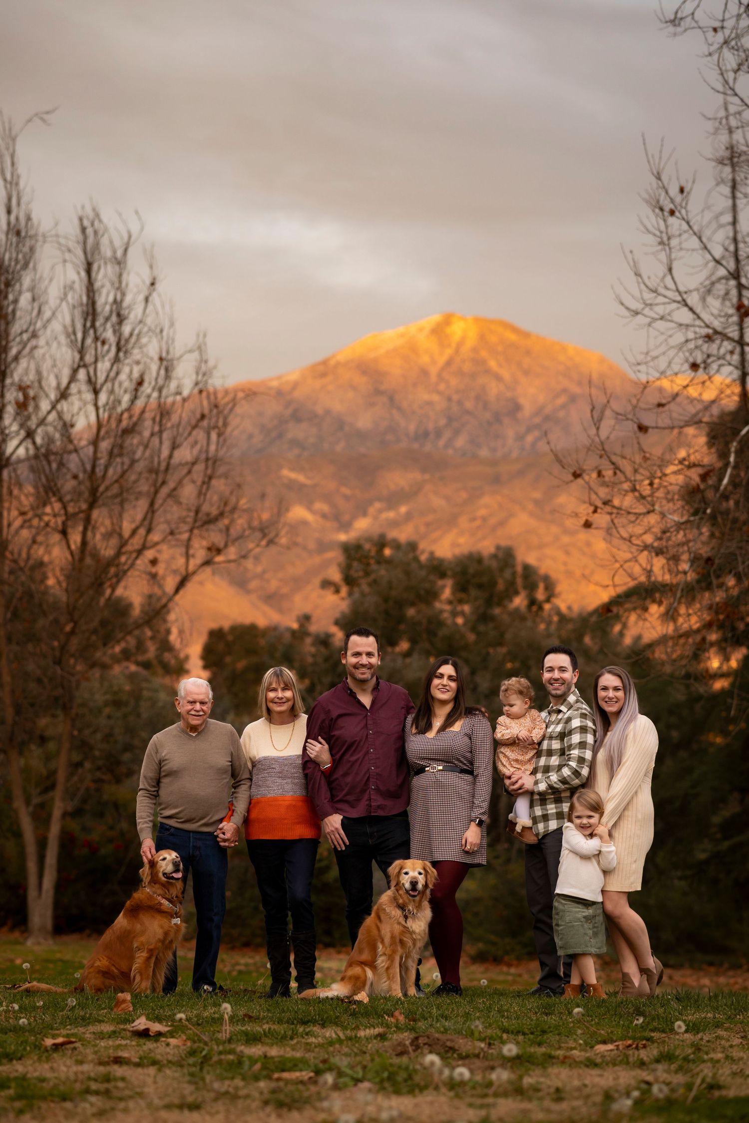 Extended family portrait with mountain backdrop at sunset including their golden retriever.