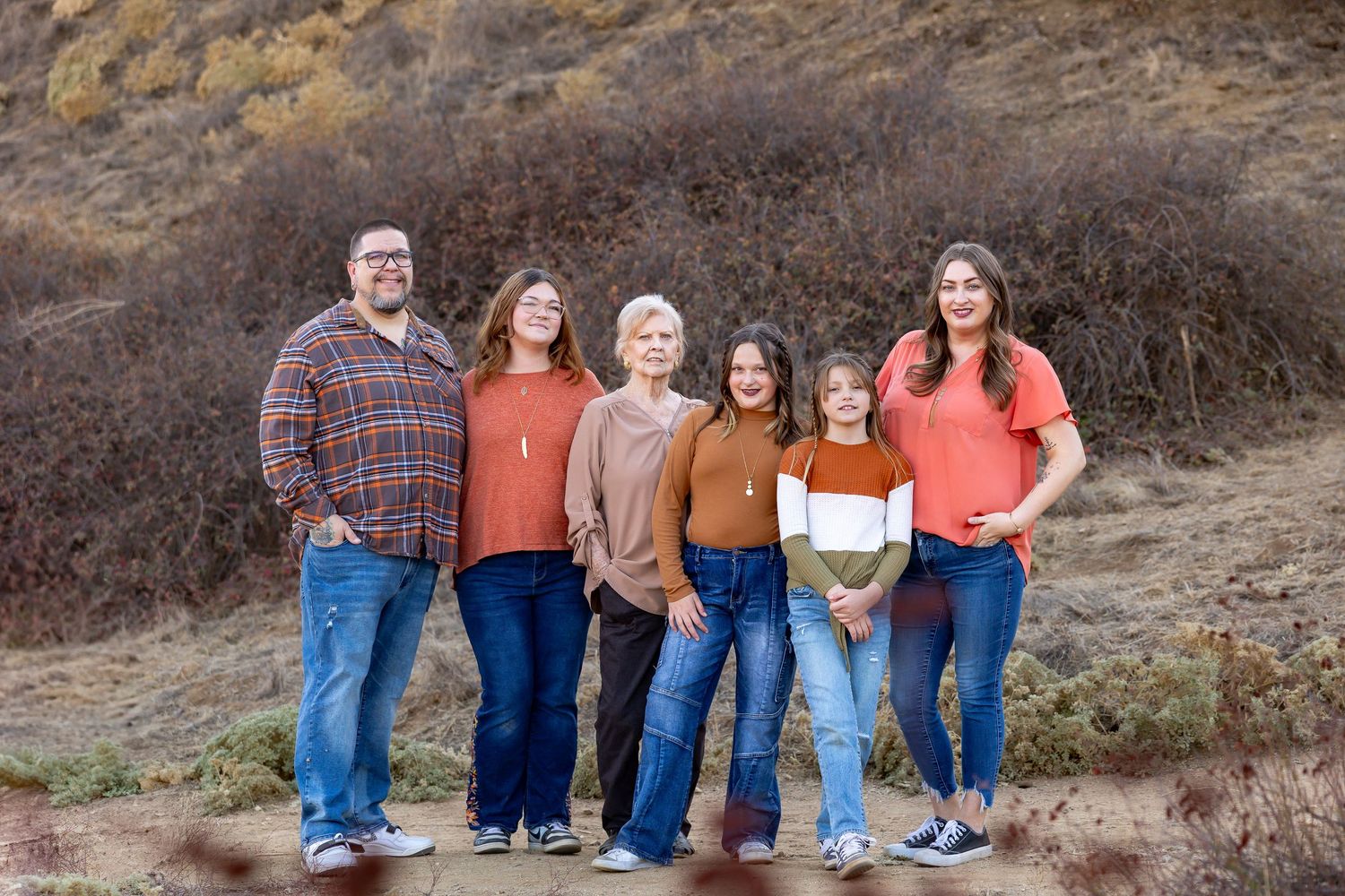 Wide shot of family members lined up against natural desert backdrop during sunset.