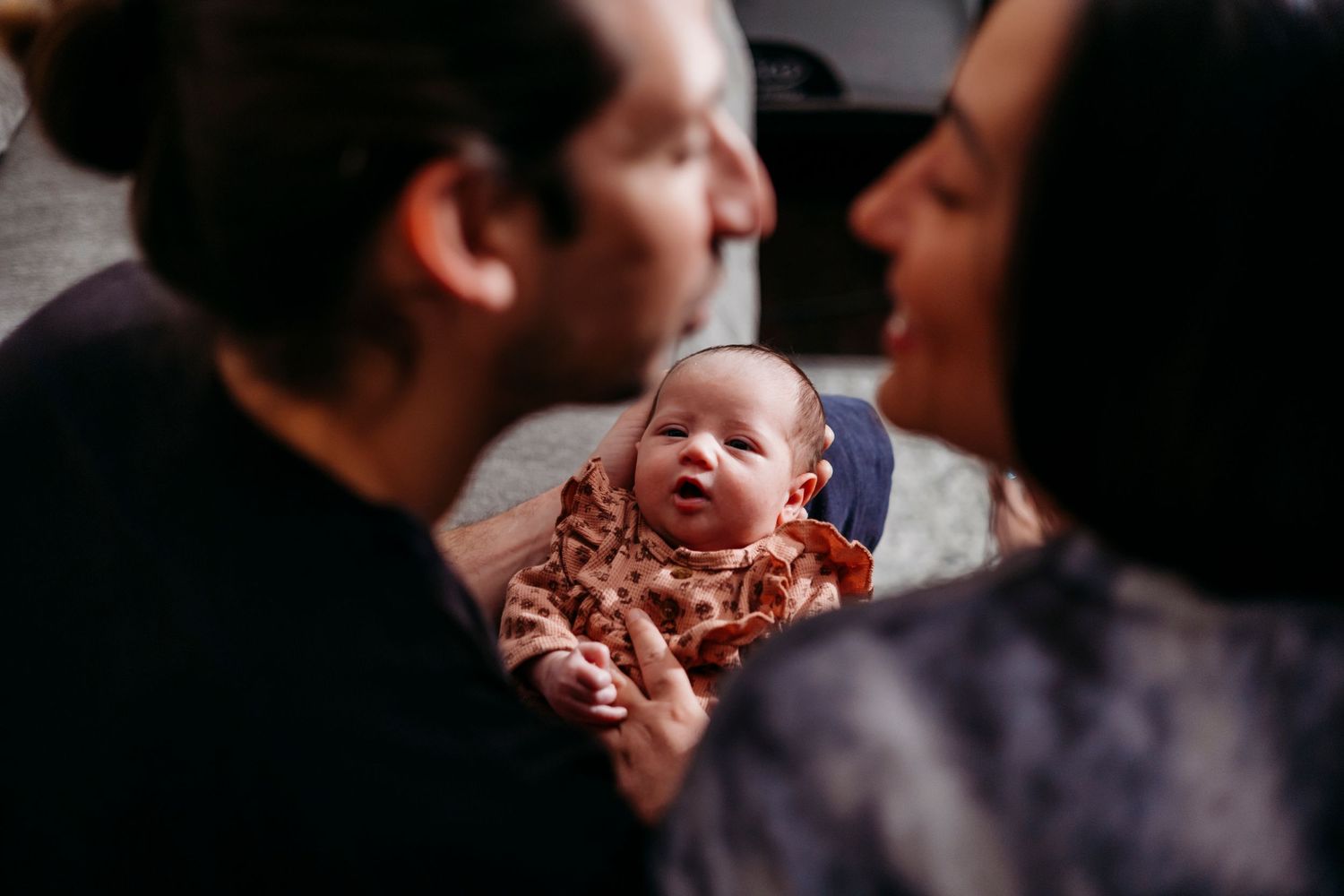 Newborn baby yawning while being held by parents in an intimate family portrait in their home in Cherry Valley.