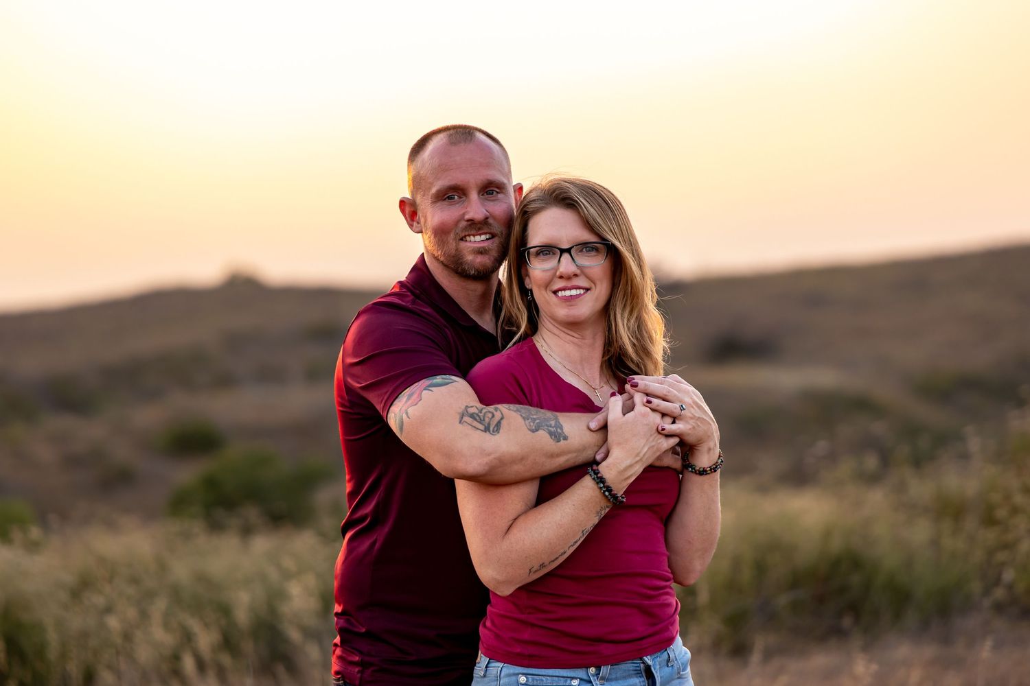 Couple sharing an intimate moment against a golden sunset backdrop on a rural road.