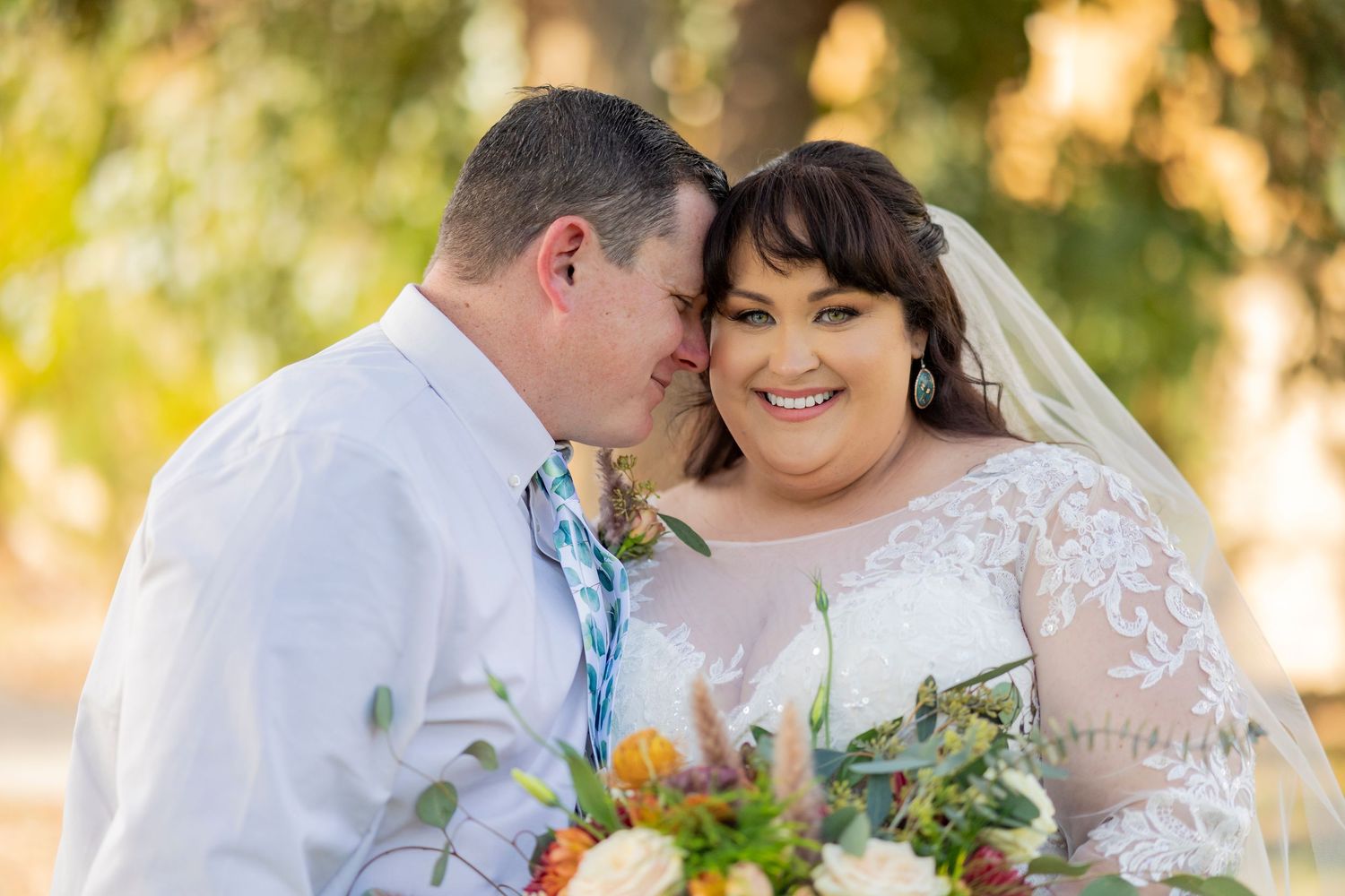 Intimate wedding portrait with floral bouquet in golden afternoon sunlight.