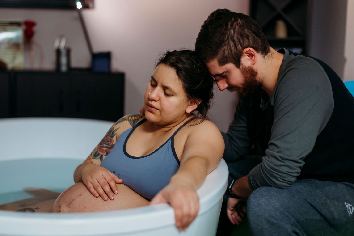 Birth scene showing support during labor in home water birth setting in Upland.