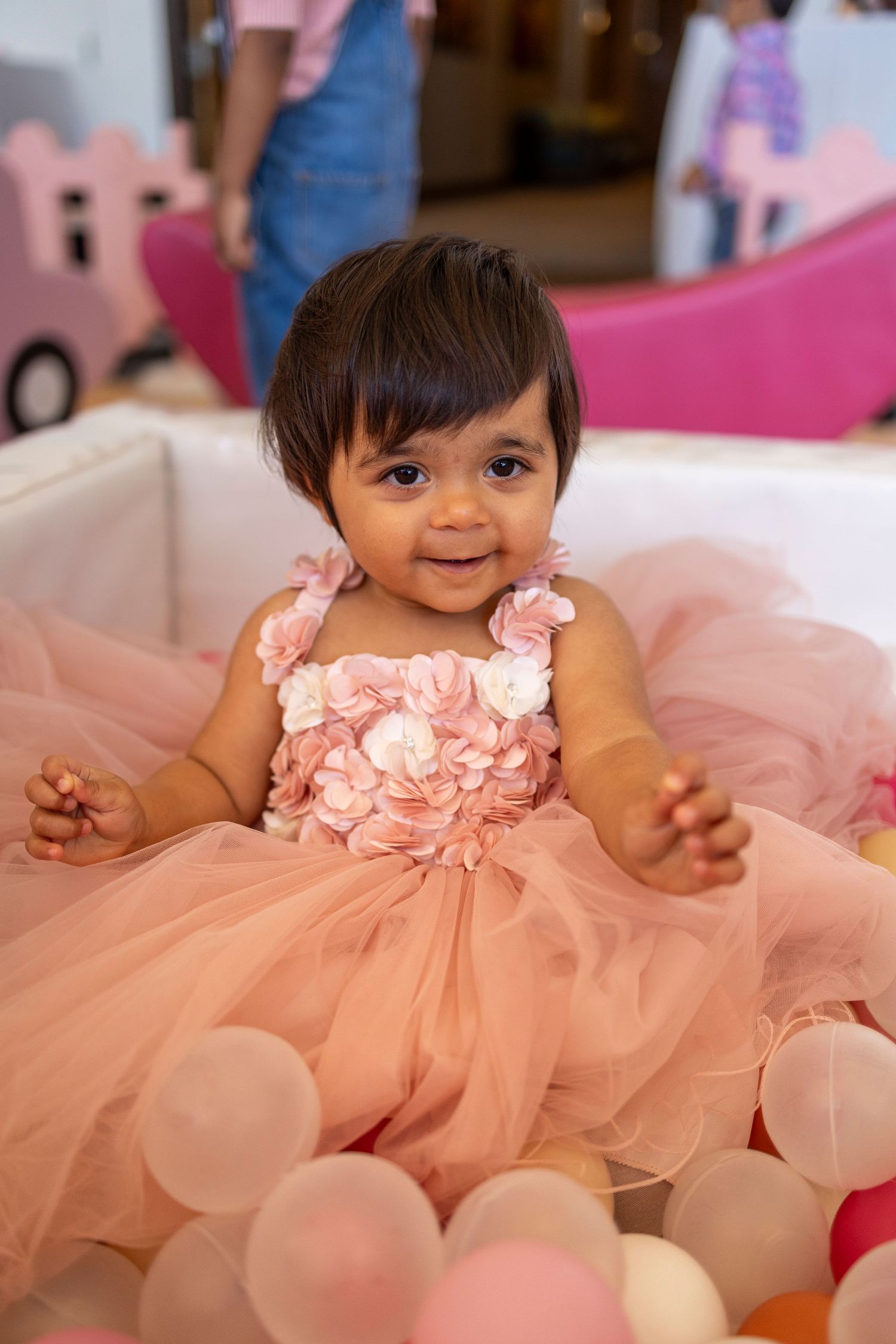 Baby wearing a peach-colored tulle dress sitting on the floor in Riverside.
