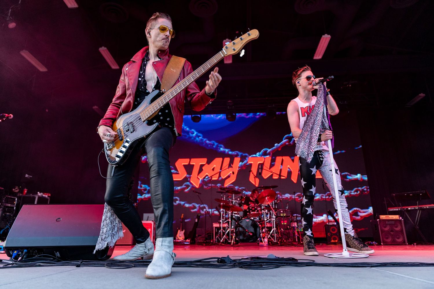 Musicians performing on stage during a rock concert with dramatic lighting.