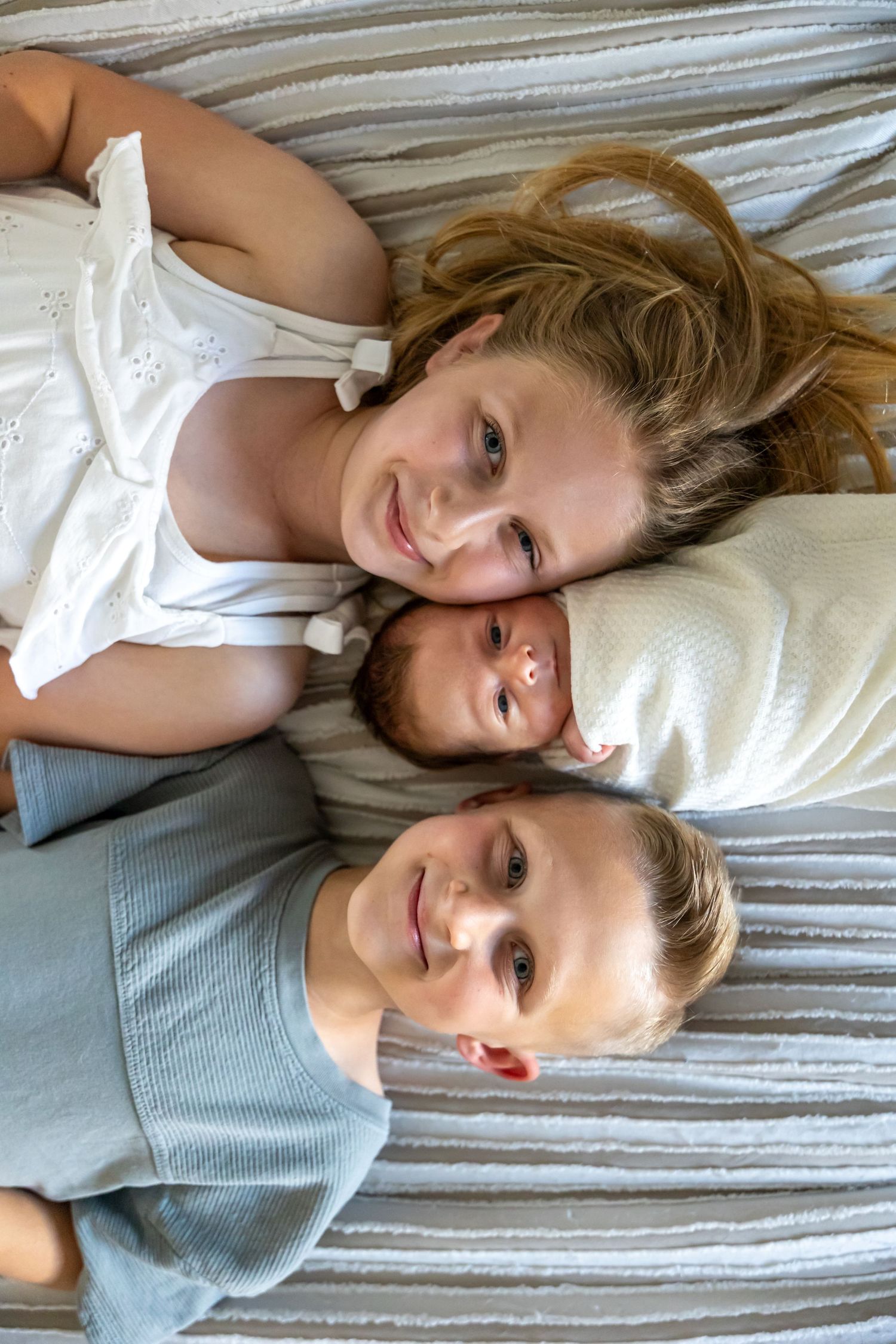 Family members lying together on striped bedding sharing joyful moments.