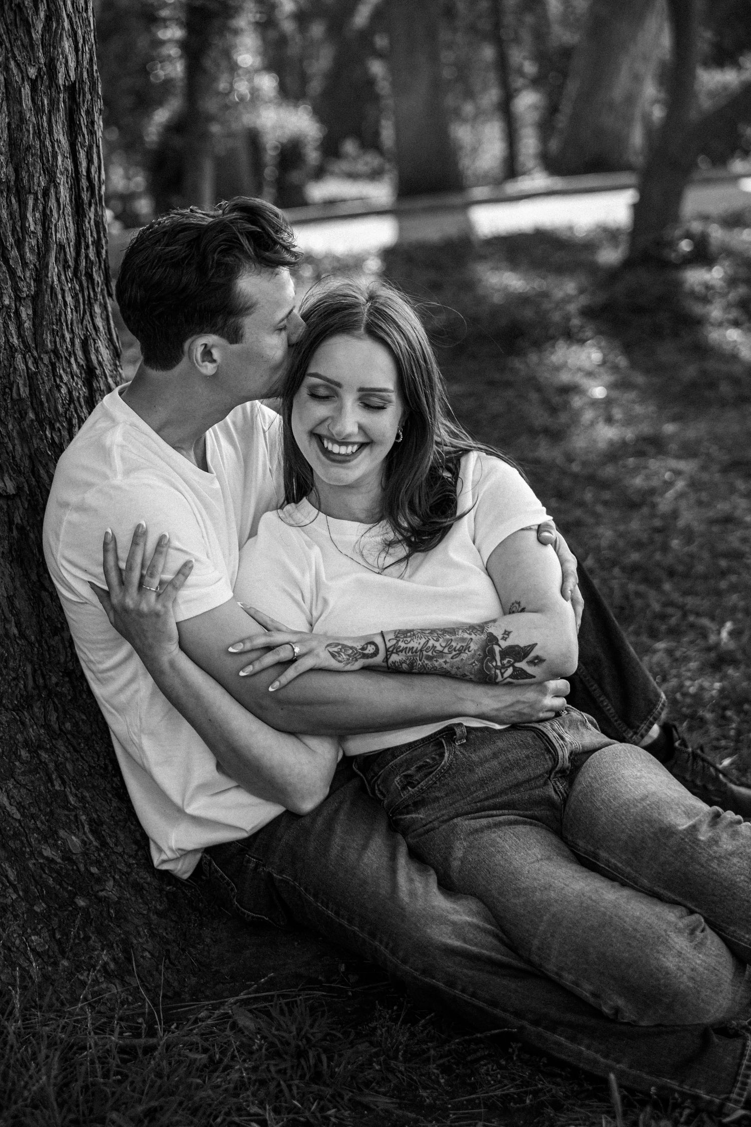 Couple relaxing together on a blanket under trees in black and white photography.