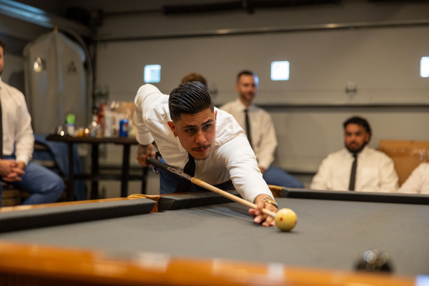 Wedding party playing pool in a casual game room setting.