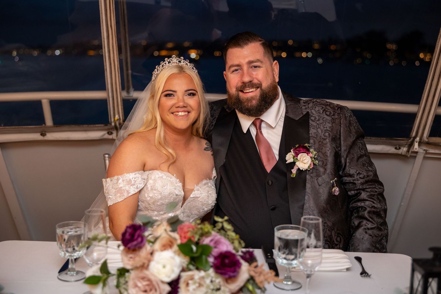 Newlywed couple sharing an intimate moment at their wedding reception dinner with floral centerpiece.