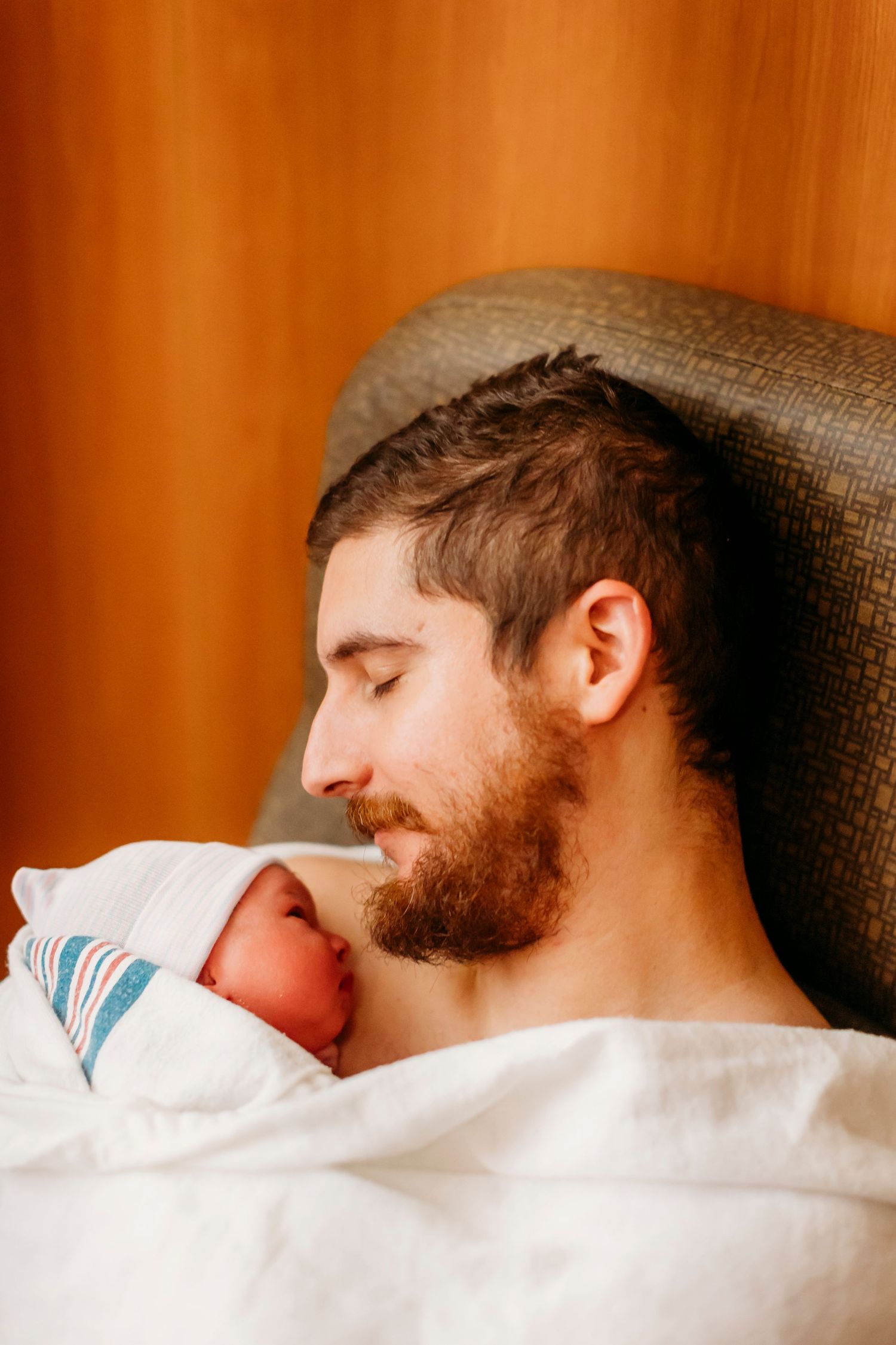 A tender moment as someone gazes at a newborn baby resting in white hospital bedding.