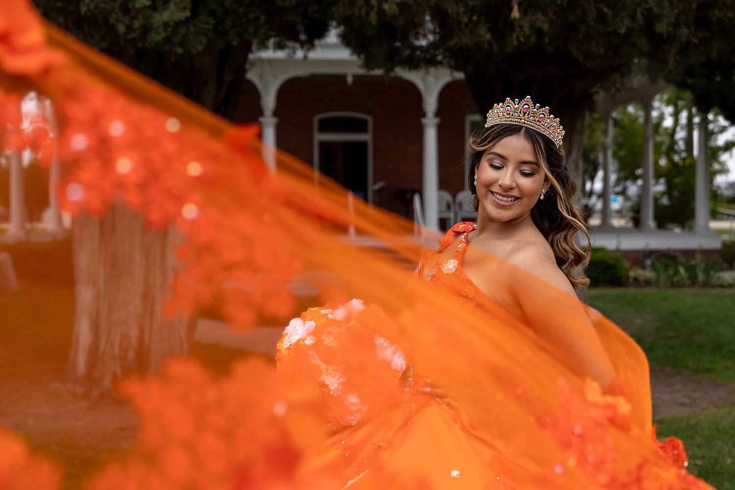 Flowing orange dress captured in motion against dark background during celebration.