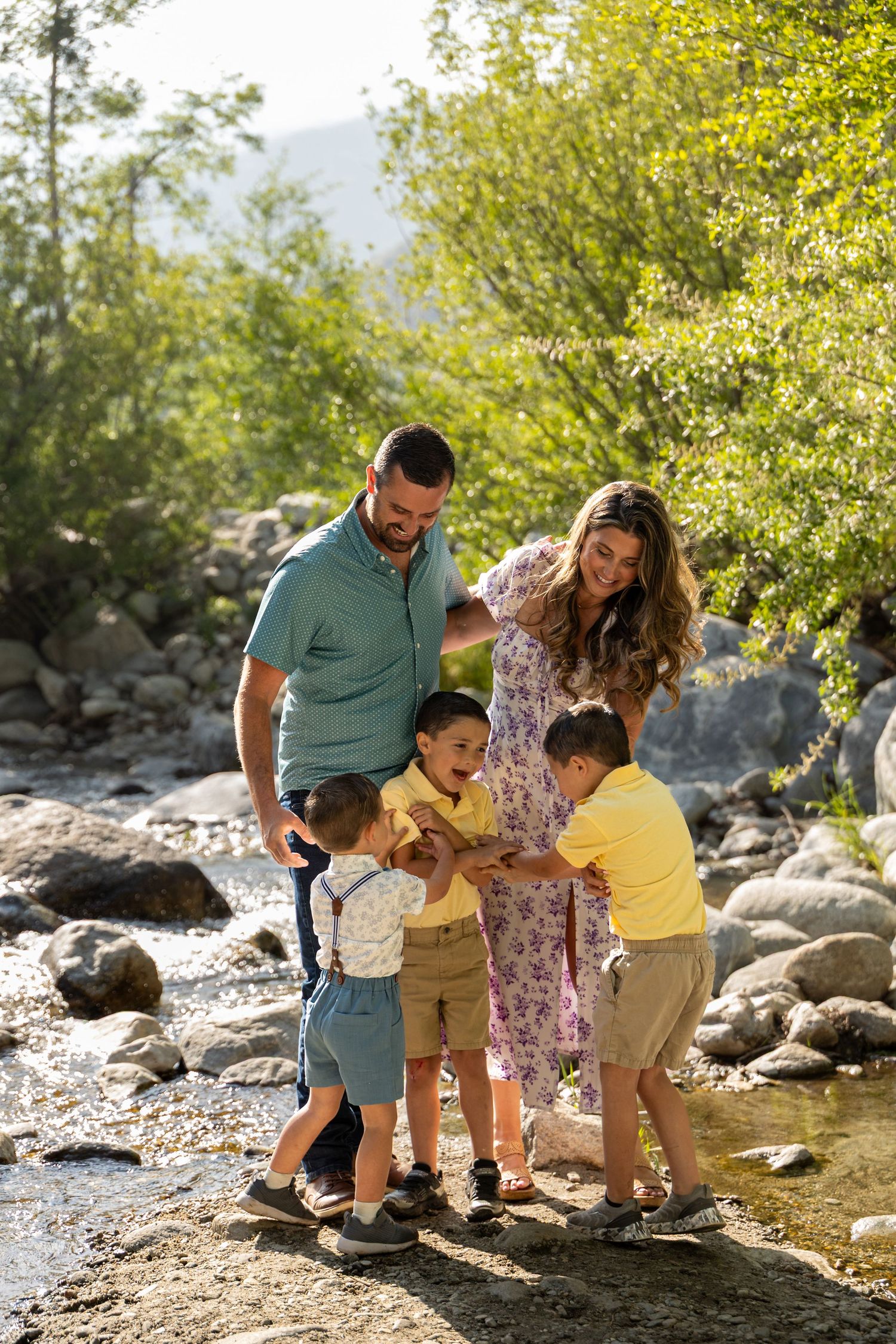 Family exploring rocky creek bed together on sunny day with yellow foliage.