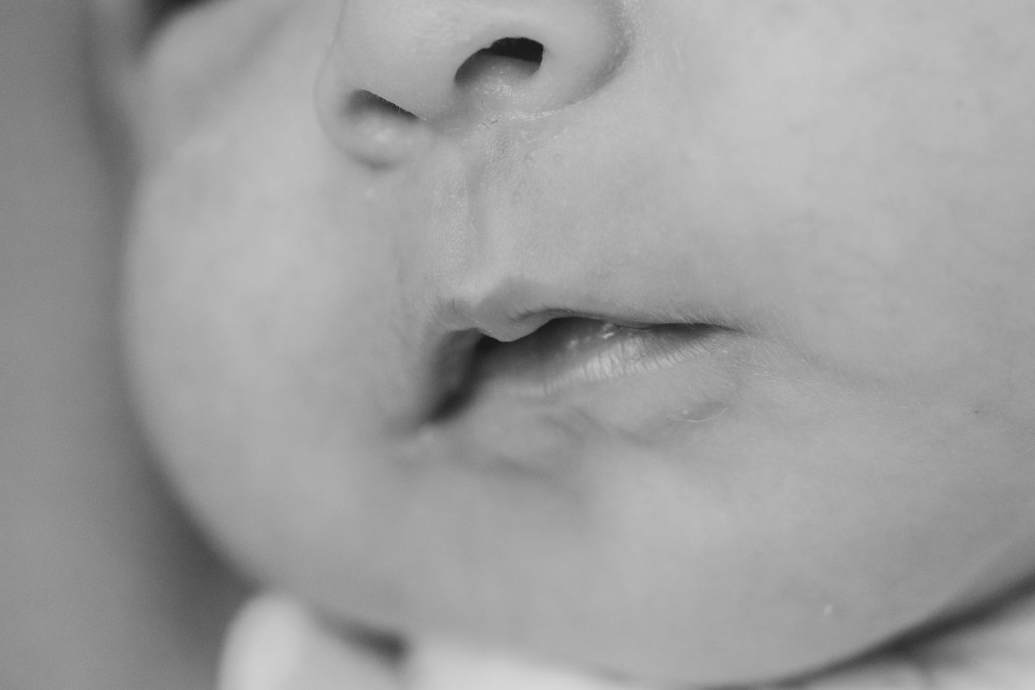 Close-up black and white portrait of tiny baby lips and nose in soft focus.