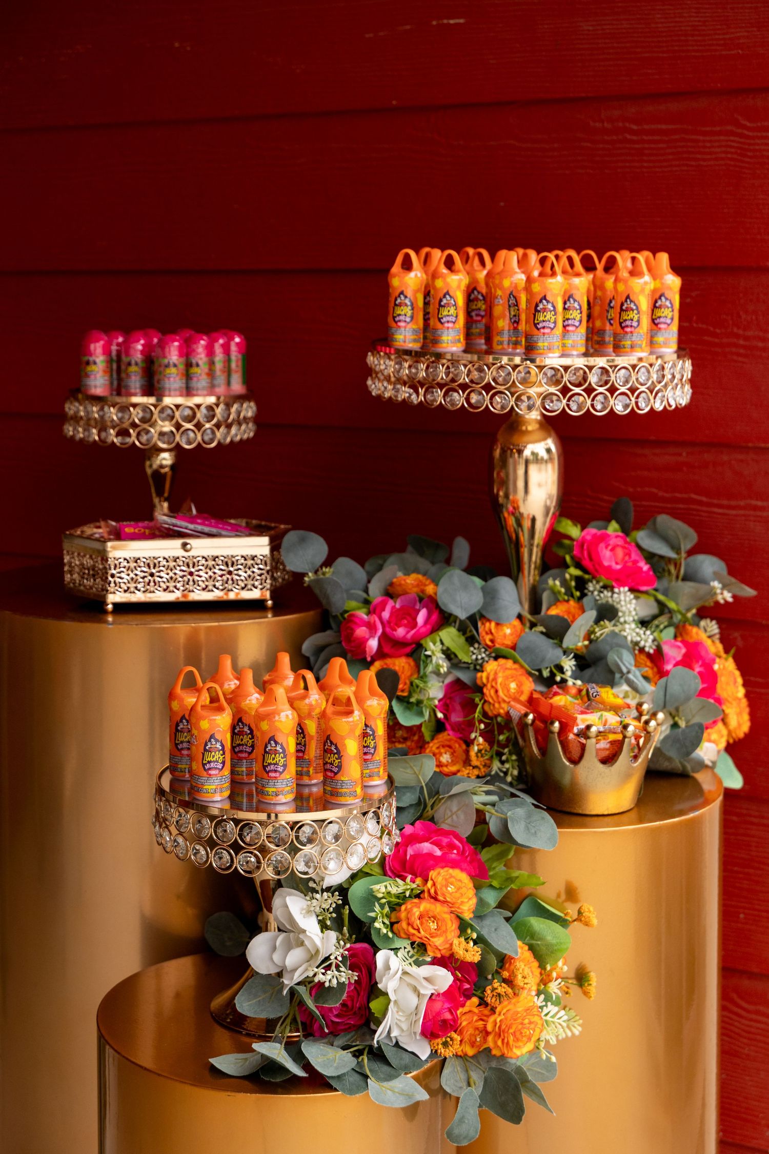 Decorative tiered display stands with colorful flowers and orange beverages for special event.