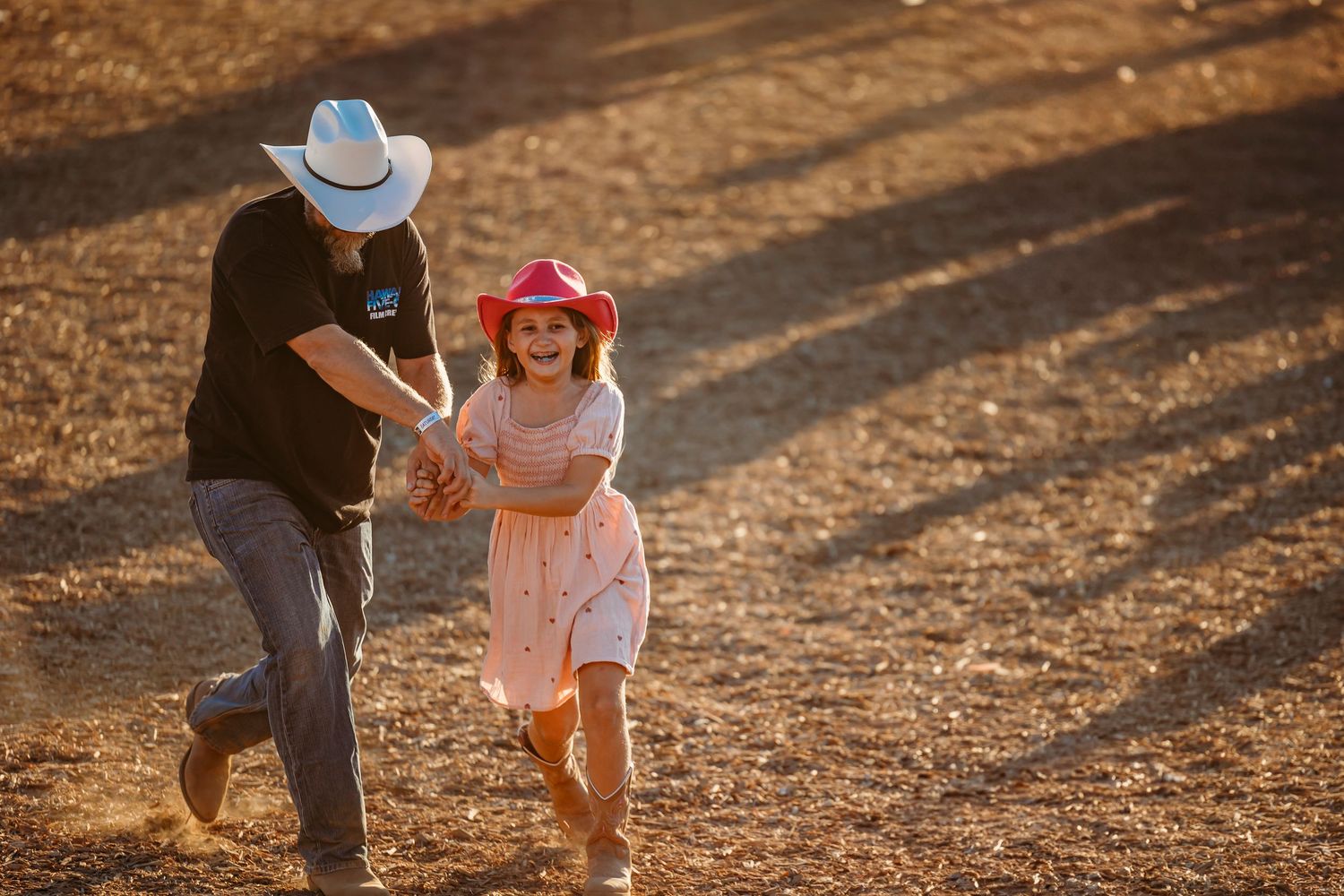 A playful moment captured at sunset with two figures running on dusty ground.