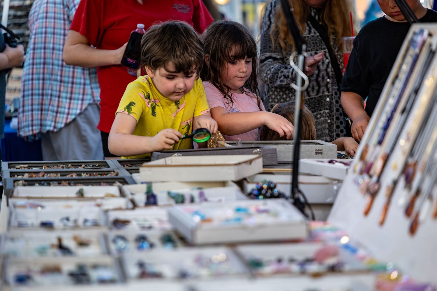 Children browse items displayed at a market vendor booth.