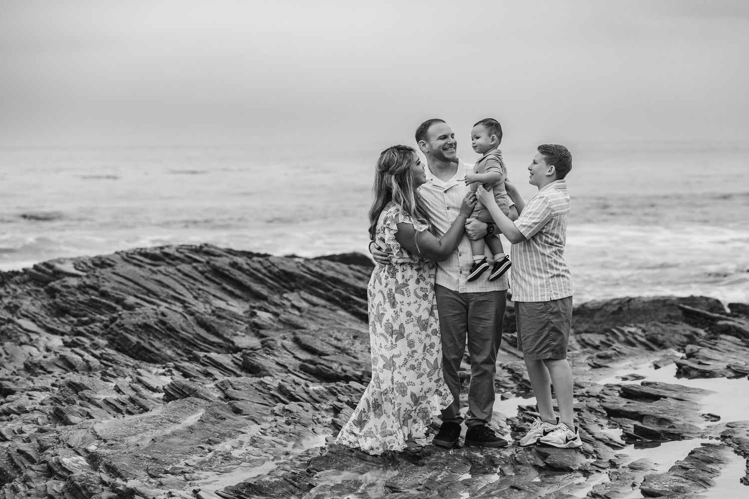 Family enjoying time together on rugged coastal rocks.
