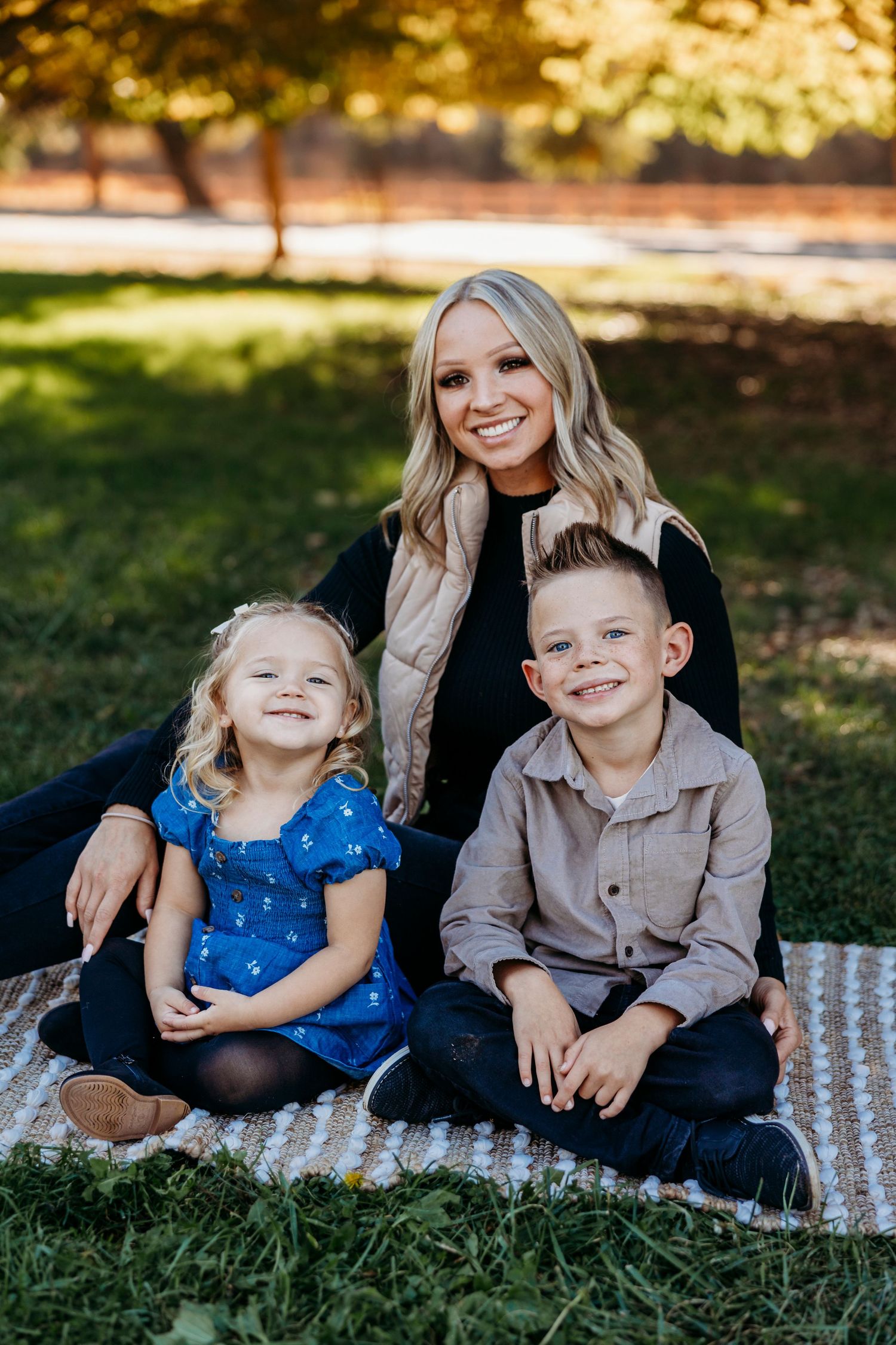 Family group sitting on blanket in grass during golden hour photo session.