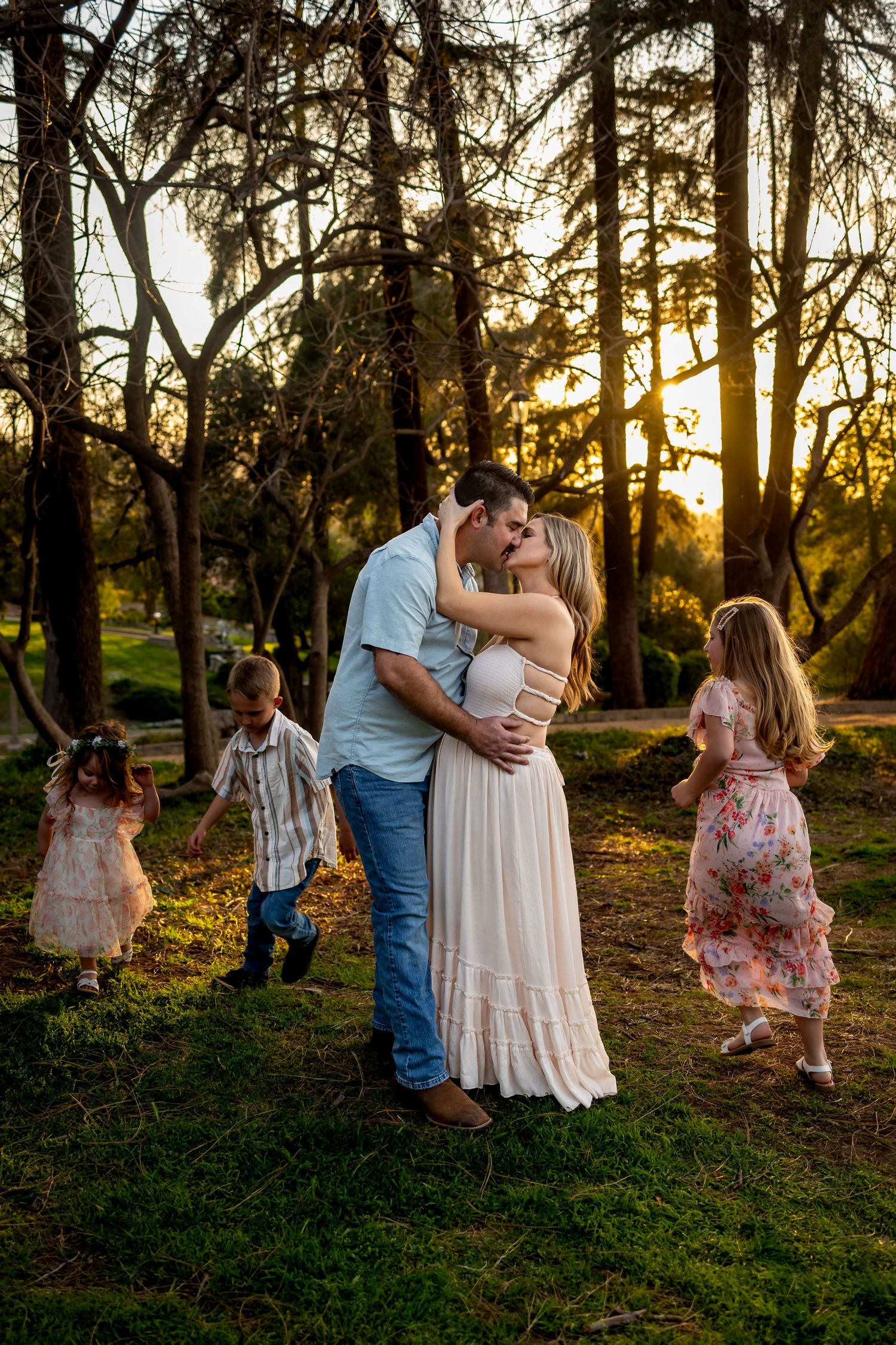 Family sharing tender moments together during a golden sunset photo session in a wooded park setting in Redlands.