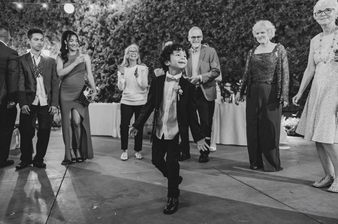 Wedding guests dance together on a hardwood floor during a reception celebration in San Juan Capistrano.