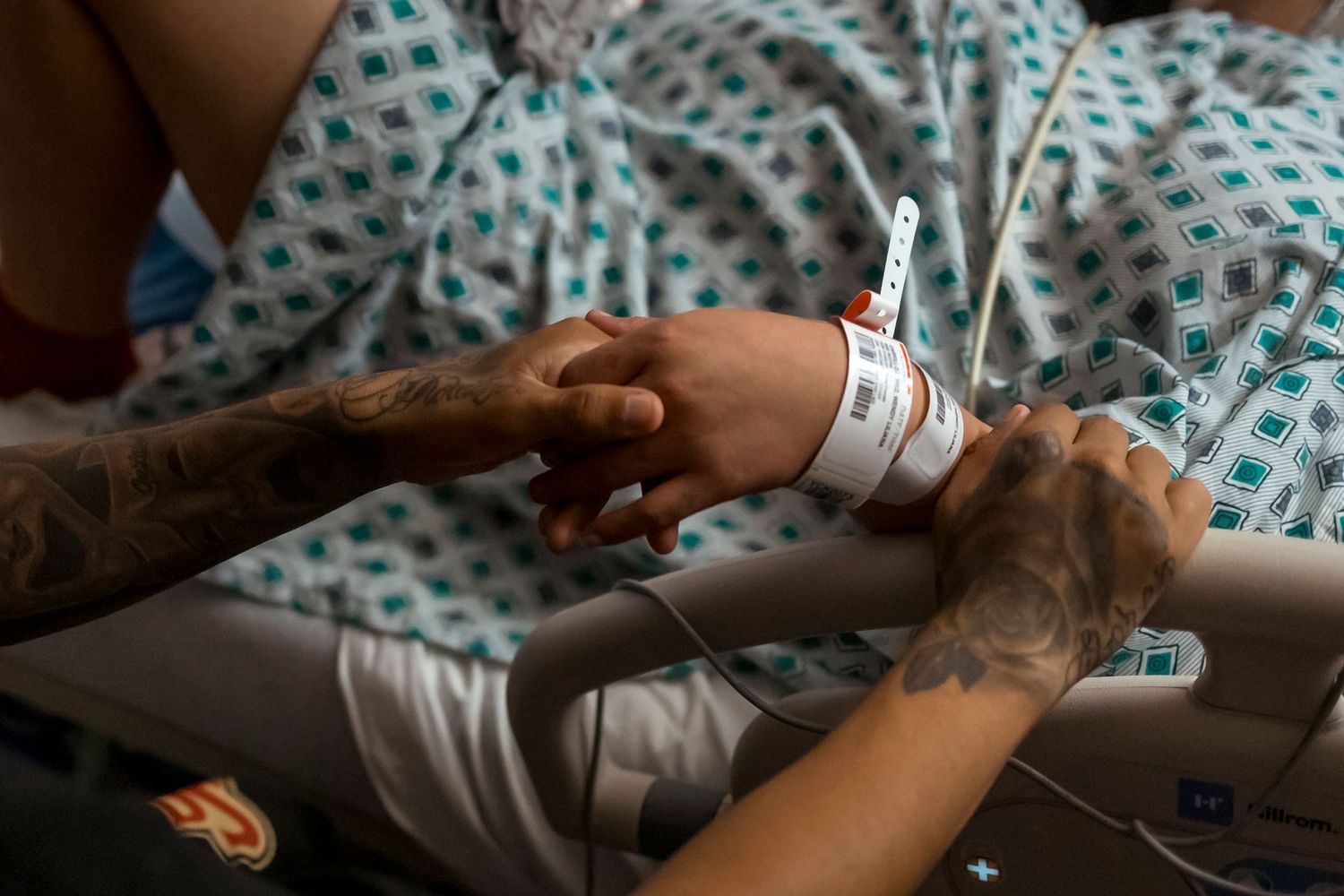 Patient wearing hospital gown with medical monitoring equipment visible.