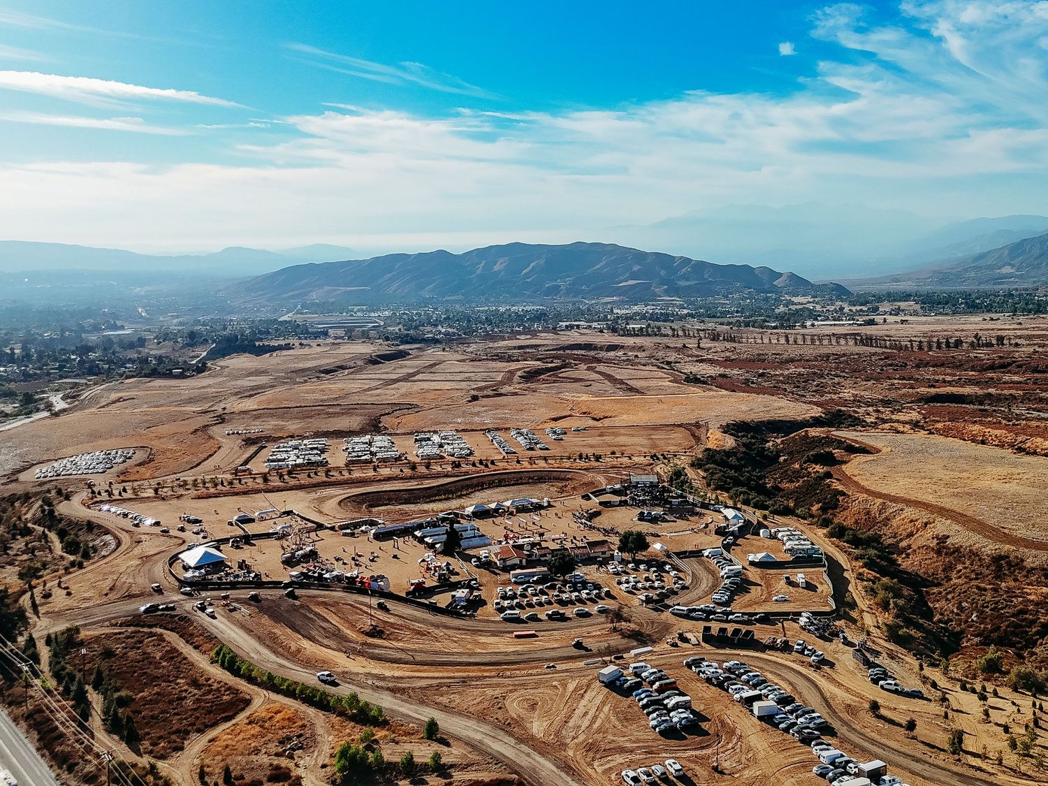 Aerial view of an RV park nestled in mountainous terrain under blue skies.