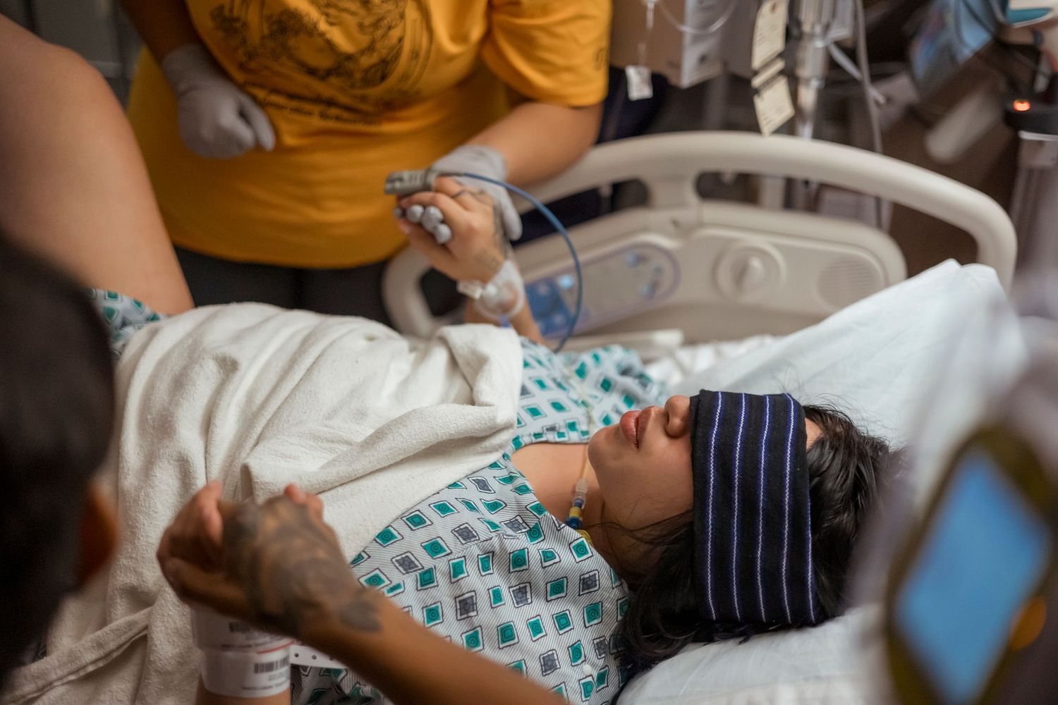 Medical staff in yellow scrubs assist with childbirth in hospital delivery room.