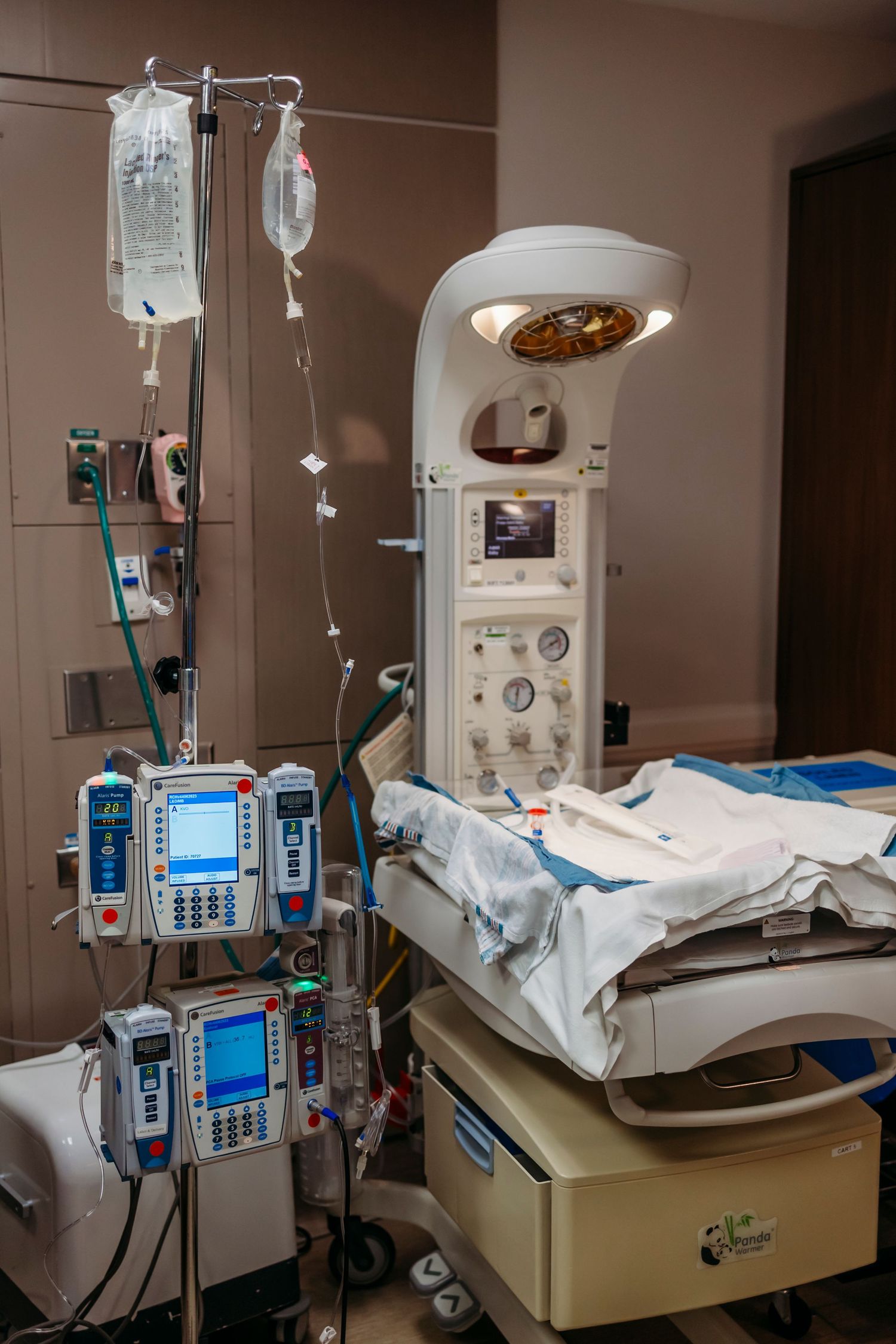 Hospital room with medical equipment and IV bags next to a patient bed.