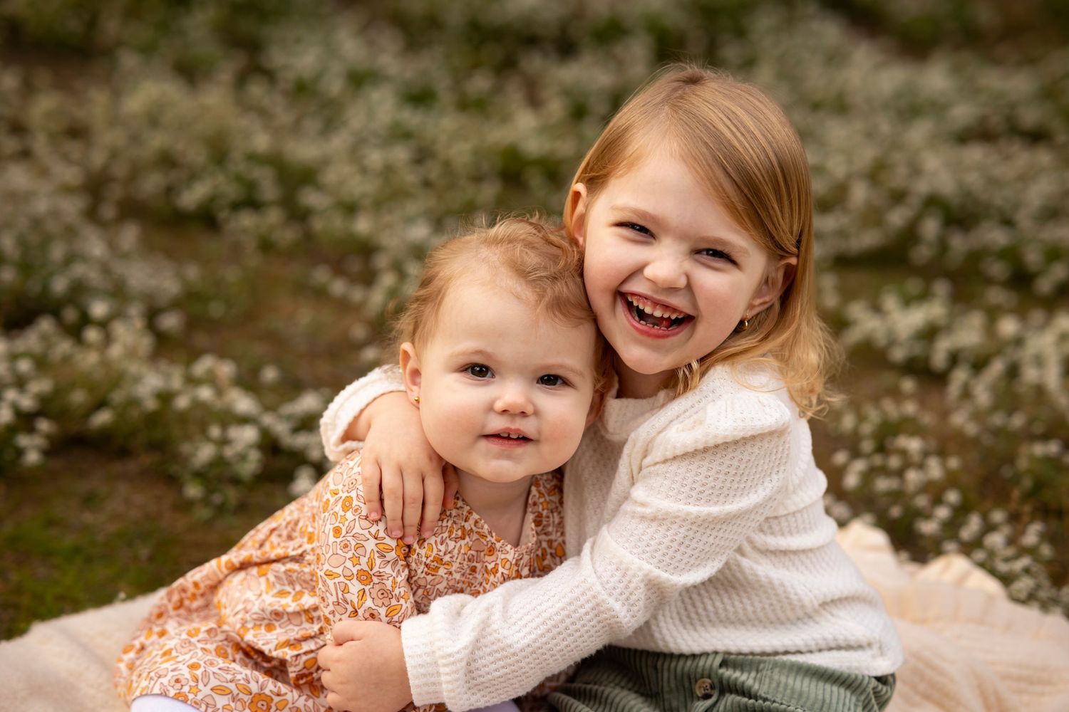 Two children sharing a tender embrace while wearing casual outfits in a natural outdoor setting.