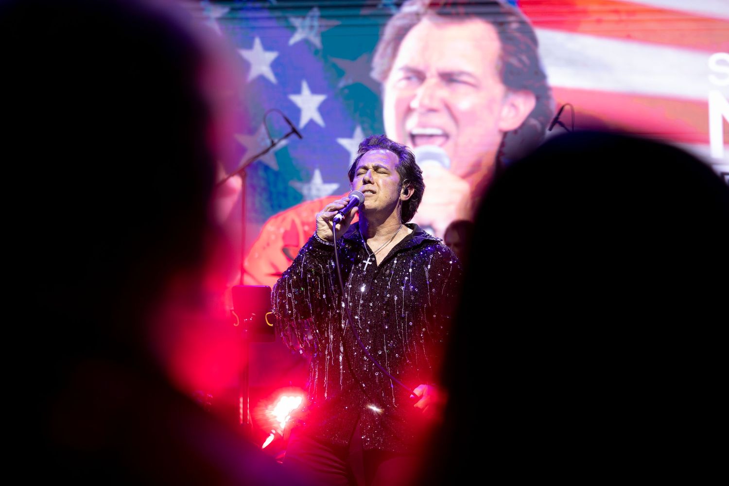 Concert performance with dramatic red white and blue lighting and American flag projection in Garden Grove.