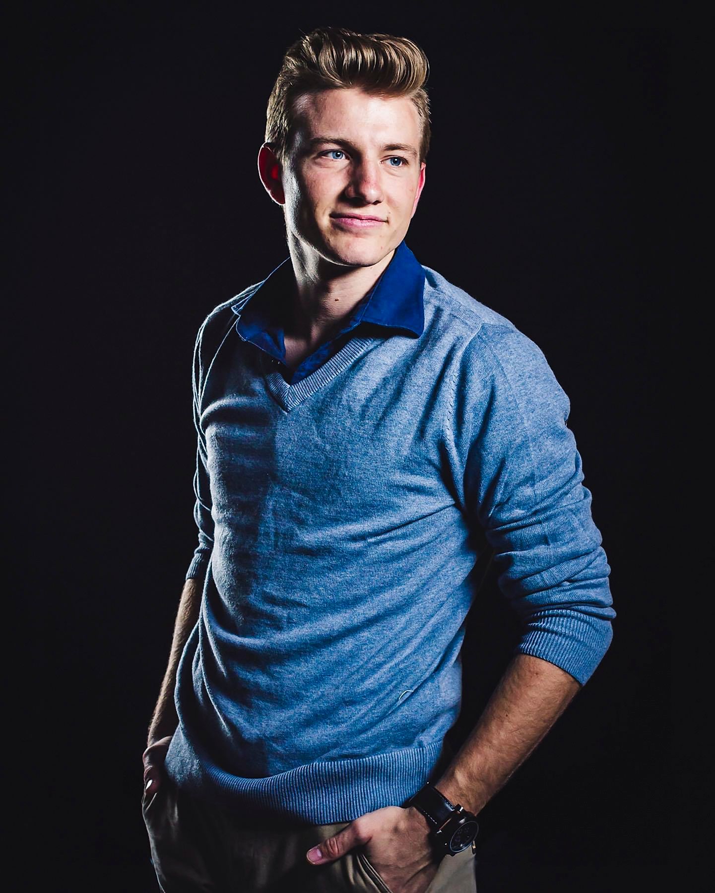 Studio portrait session against dark background featuring blue sweater.